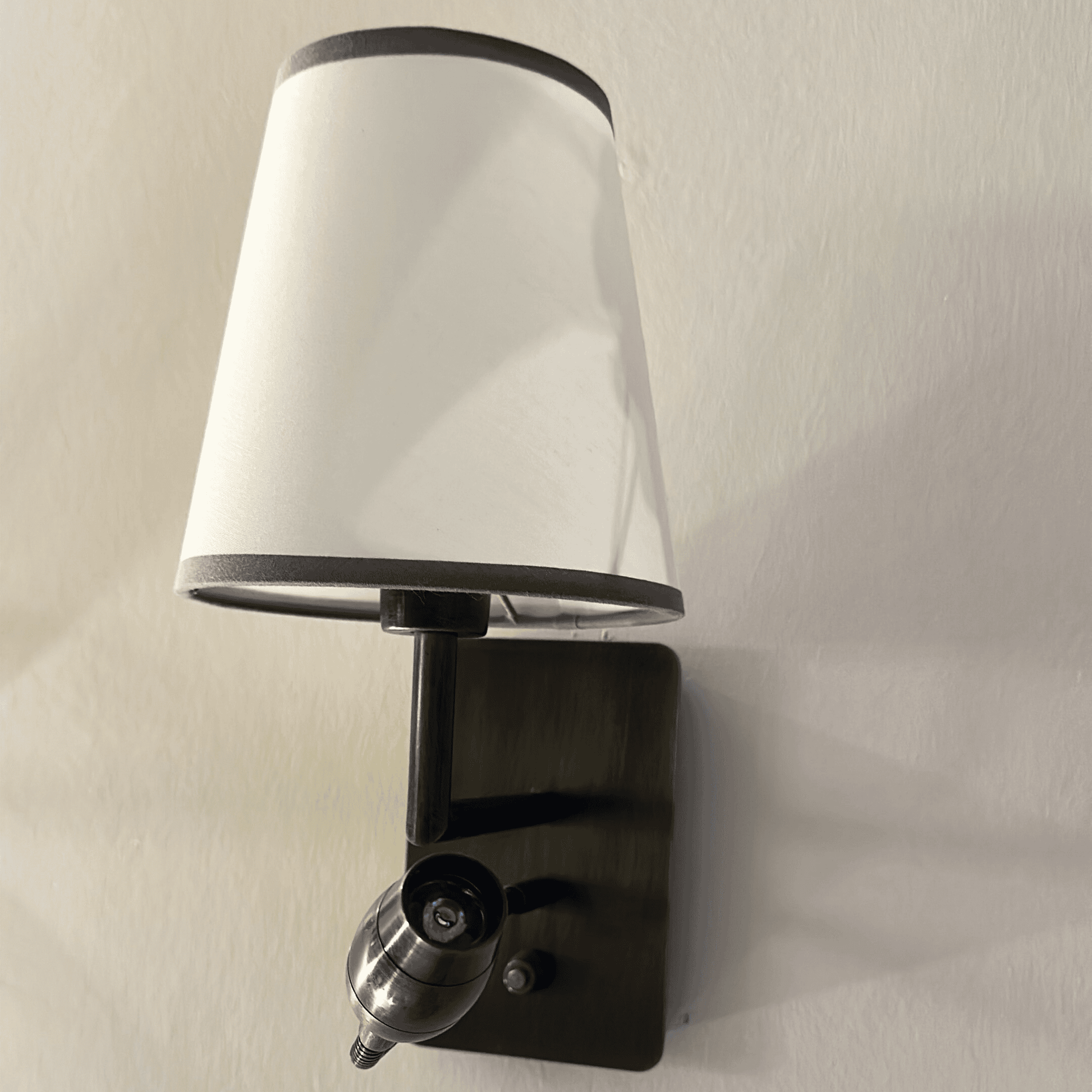 Wall sconce with white fabric shade and built-in reading light for modern interior lighting.