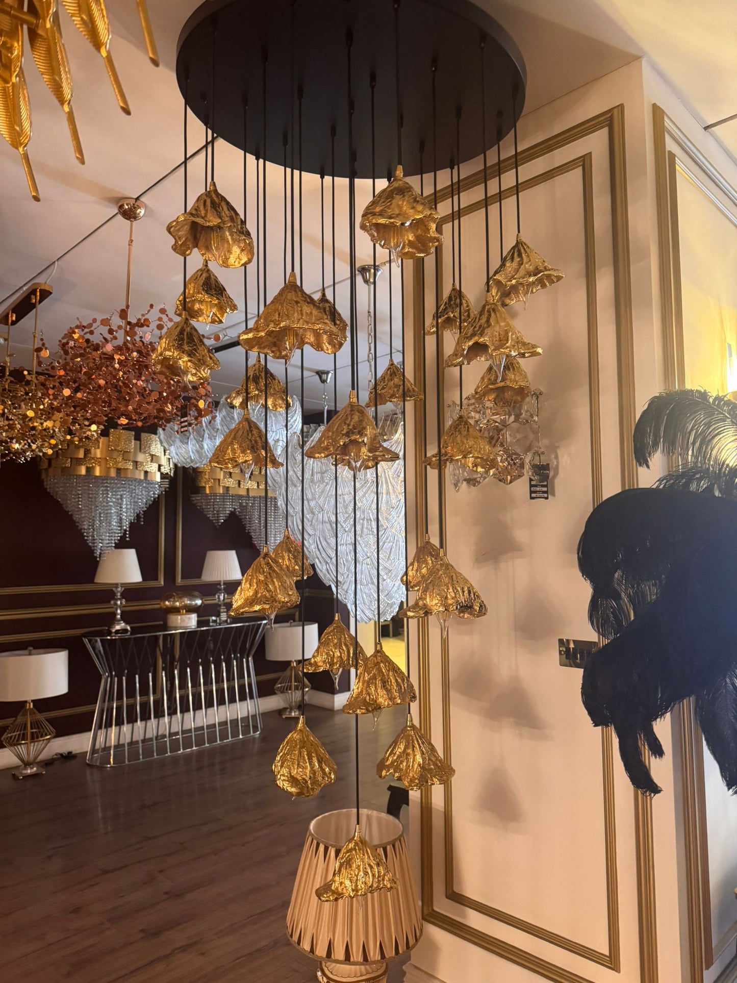 Multi-tiered pure brass leaf pendant lights hanging in a high-end showroom interior.