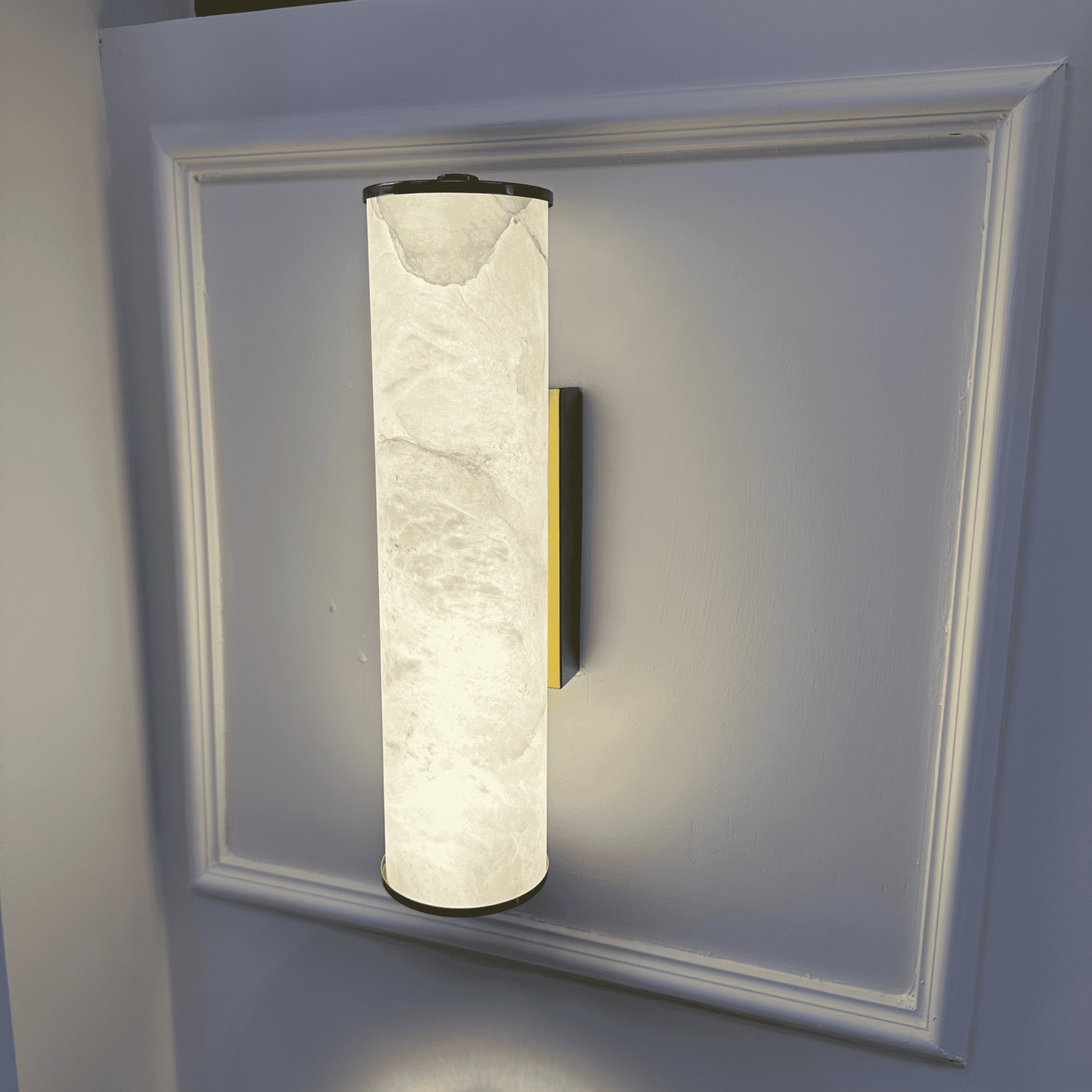 Vertical natural alabaster wall sconce with brass accent and soft ambient lighting.