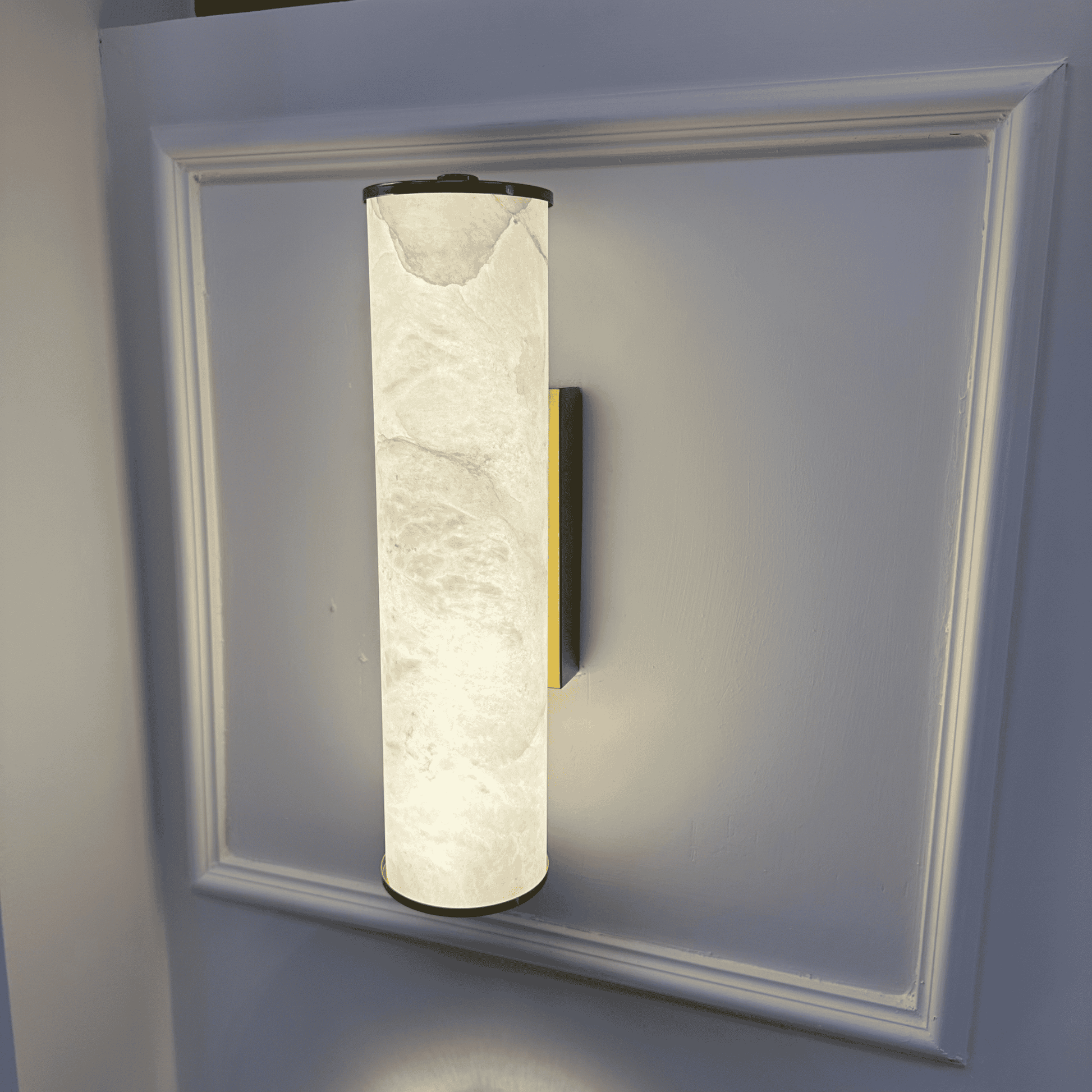Vertical natural alabaster wall sconce with brass accent and soft ambient lighting.