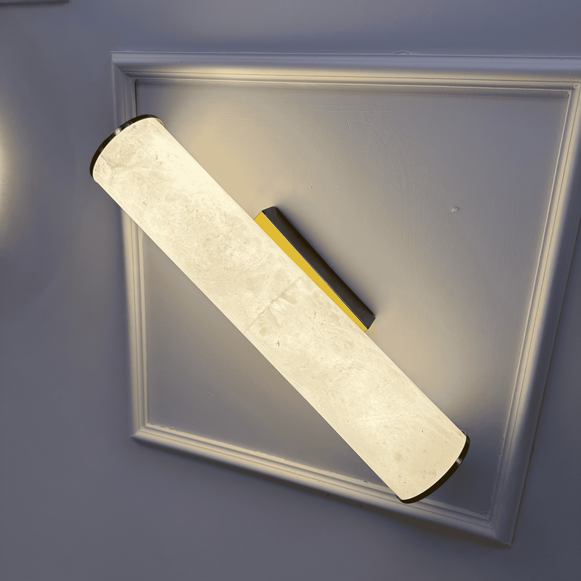 Horizontal natural alabaster wall sconce with a sleek linear design mounted on a paneled interior wall.