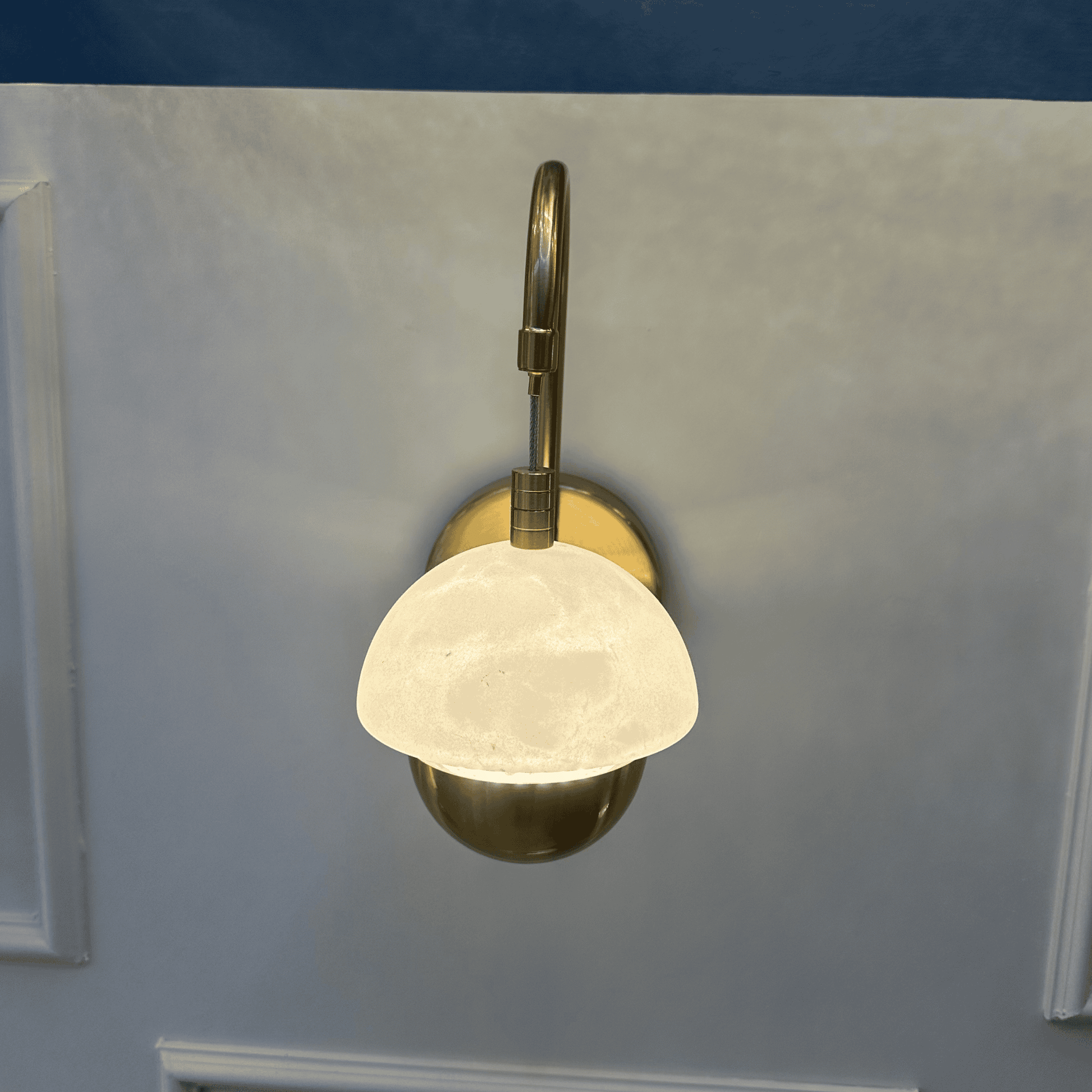 Overhead view of marble sconce with a brass mount and softly glowing dome.