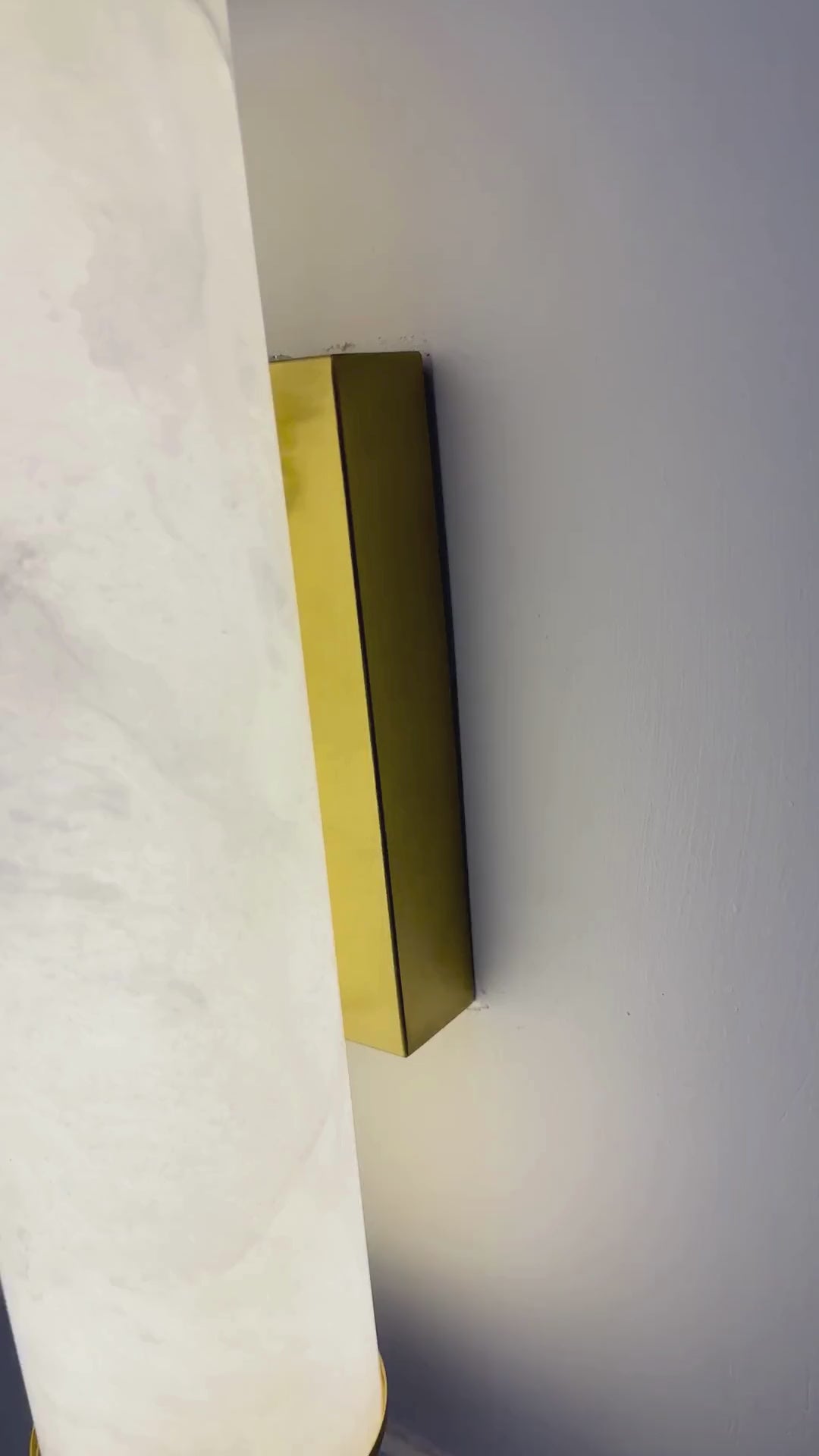 Horizontal natural alabaster wall sconce with a sleek linear design mounted on a paneled interior wall.