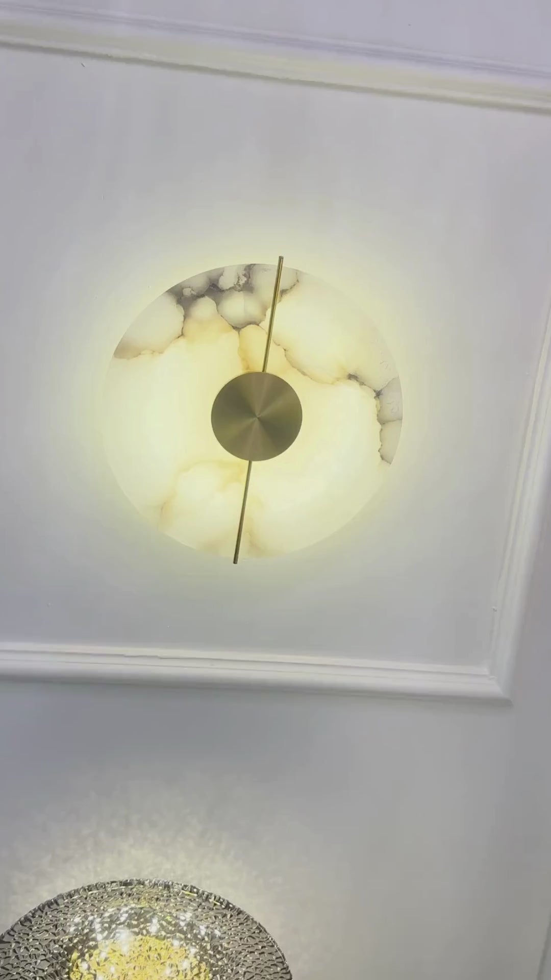 Illuminated marble sconce installed on a paneled white wall.
