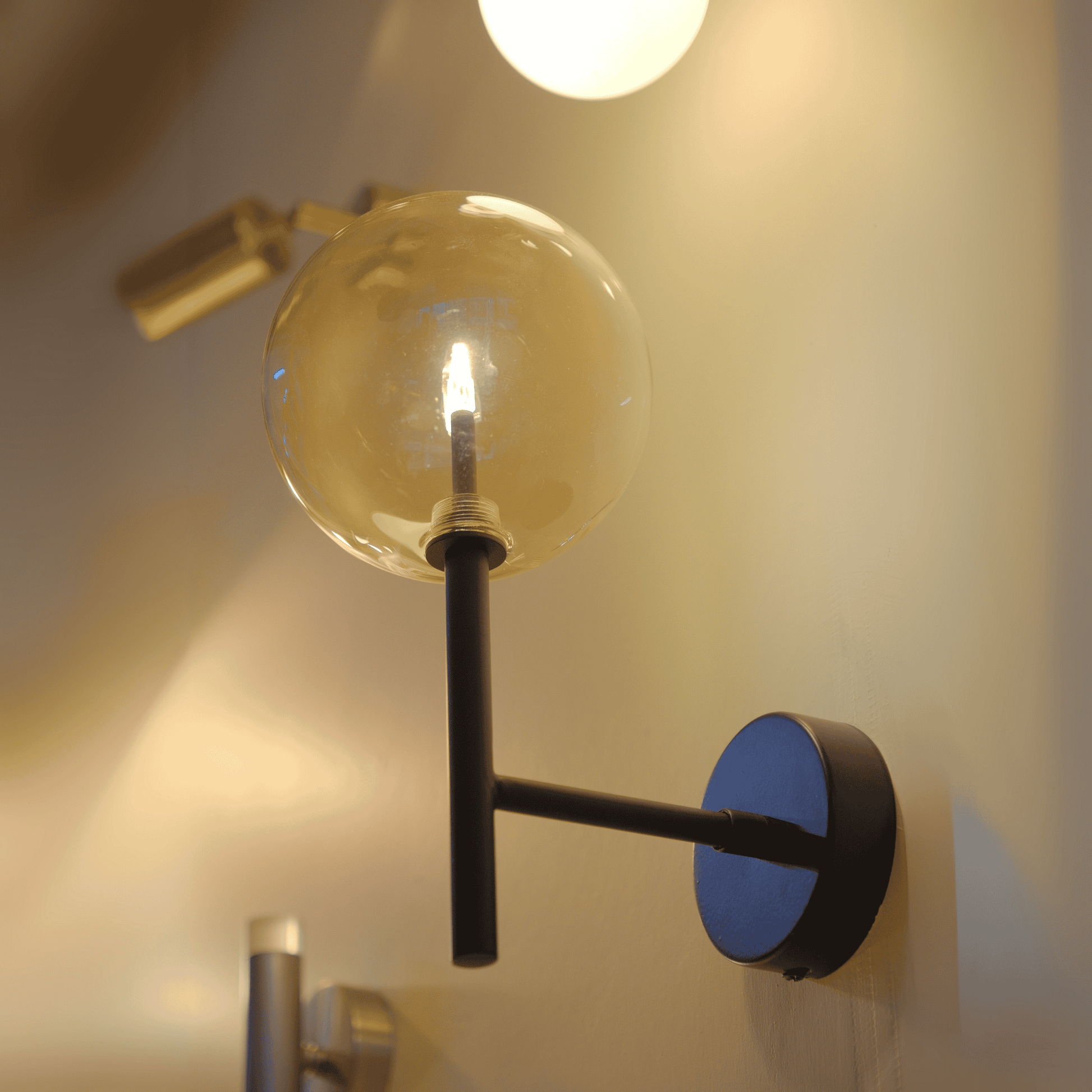 Tall black arm wall sconce with clear LED globe in a contemporary interior.