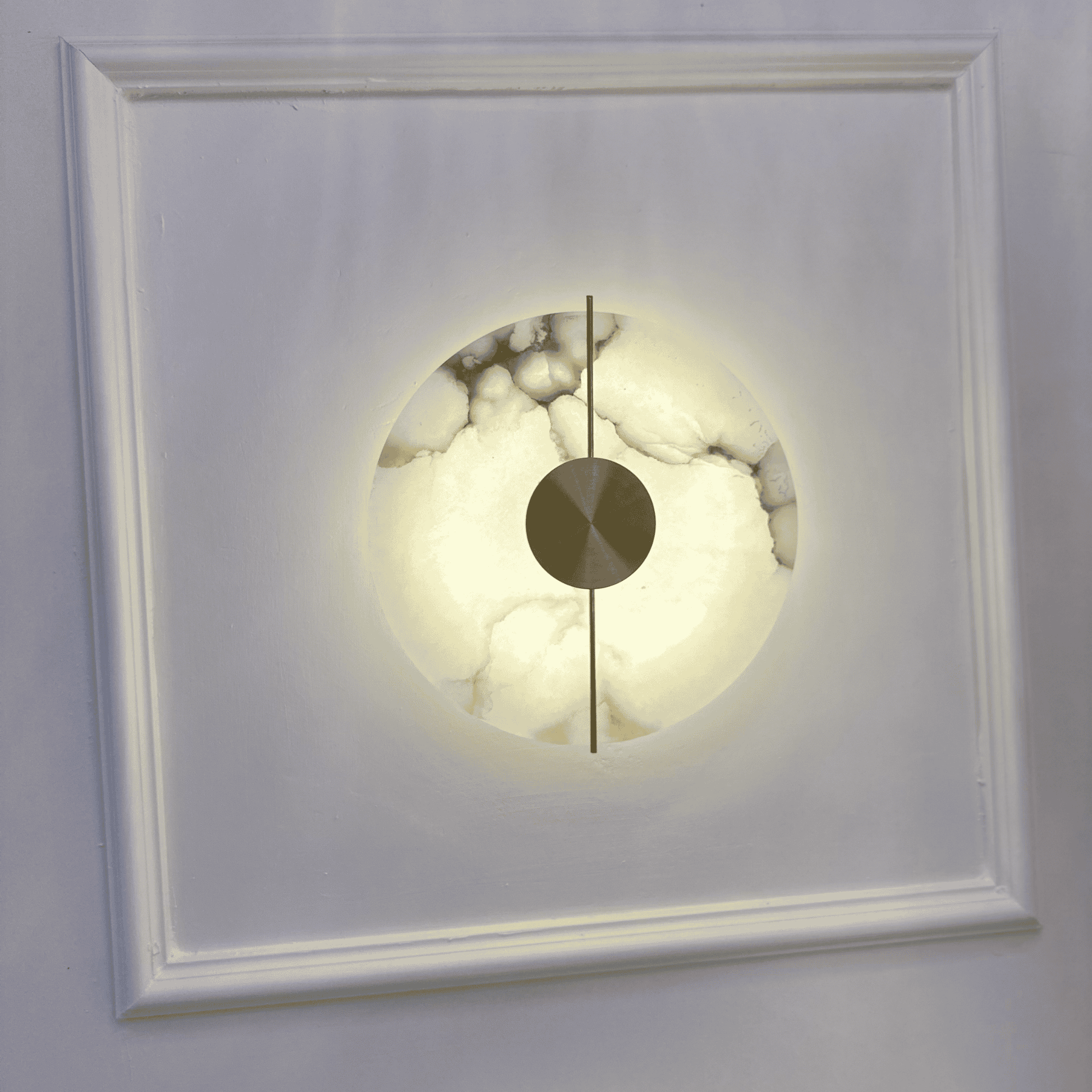 Circular marble sconce with warm ambient light mounted on a decorative wall panel.