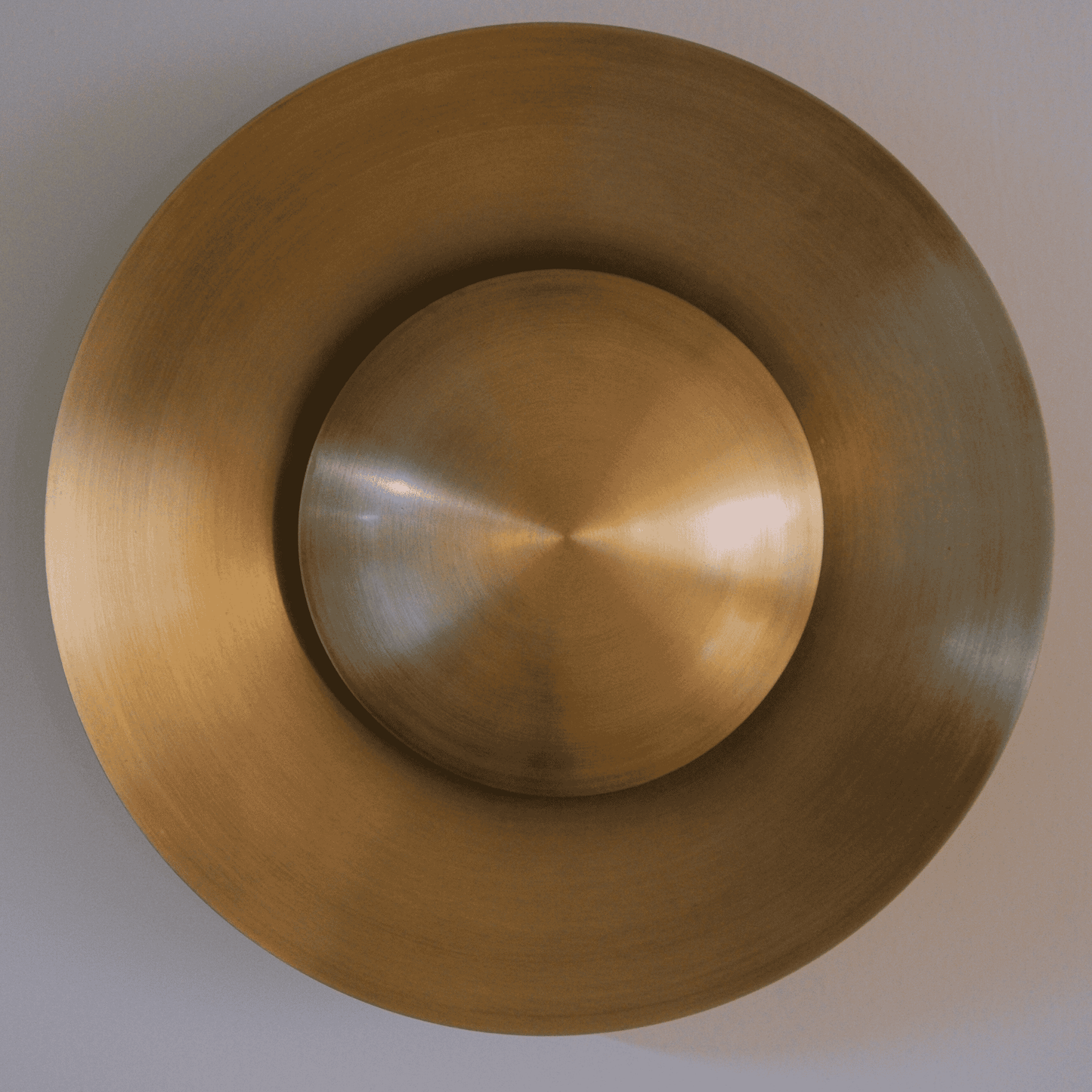 Satin brass round wall sconce with concentric form providing elegant contemporary interior lighting.