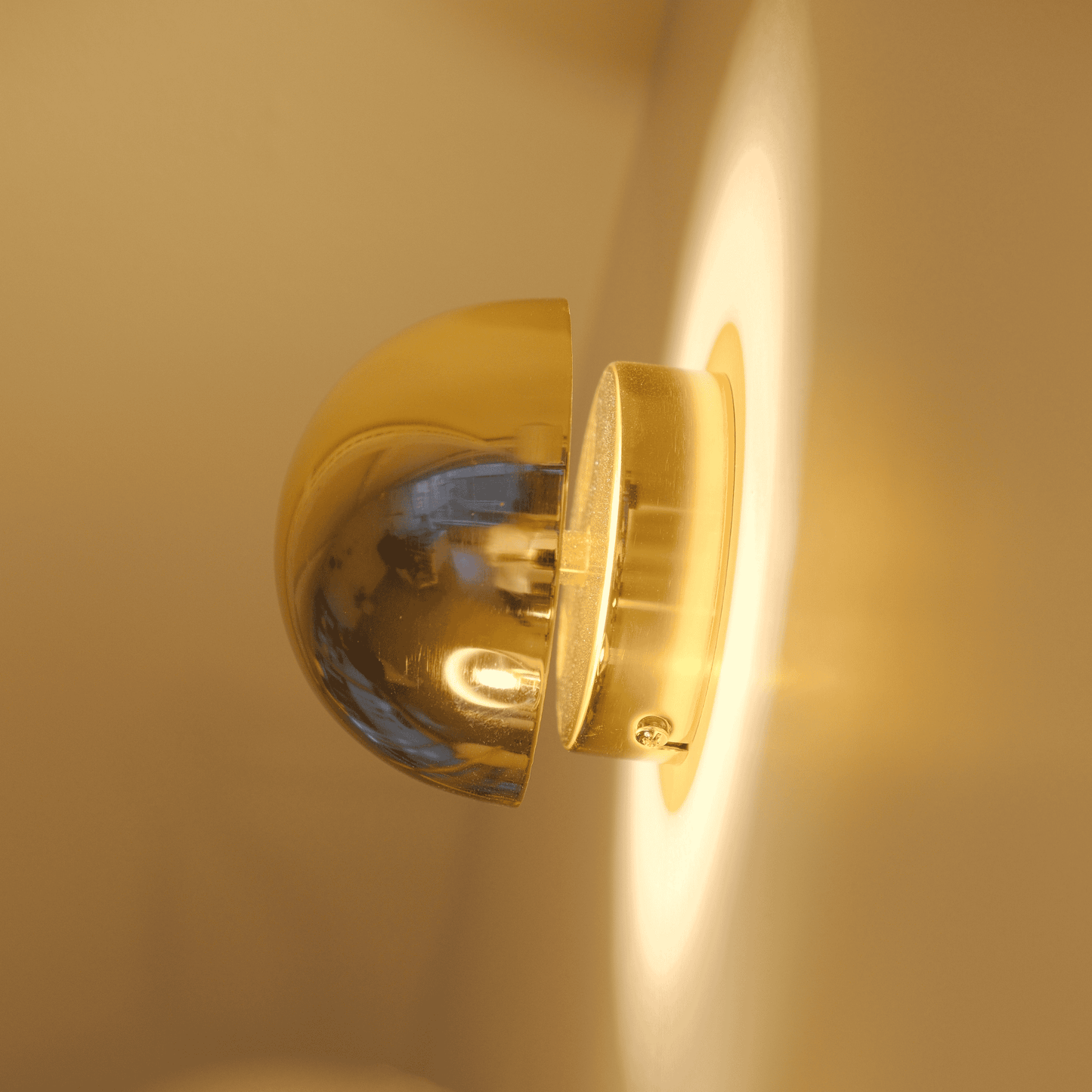 Side view of a brass wall sconce emitting indirect soft light along the wall.