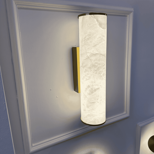 Side view of vertical natural alabaster wall sconce with brass mount and cylindrical design.