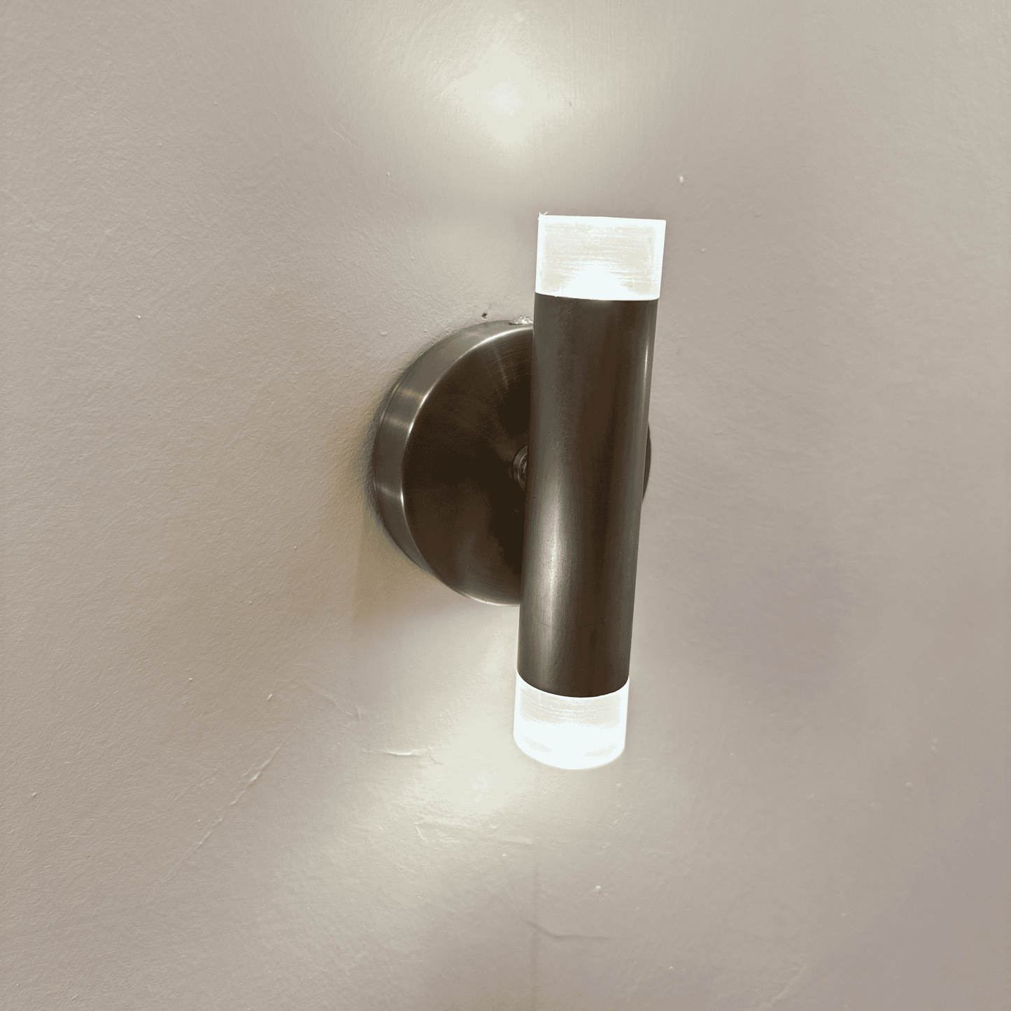 Vertical brushed metal LED wall sconce with frosted acrylic ends for soft, modern interior lighting.