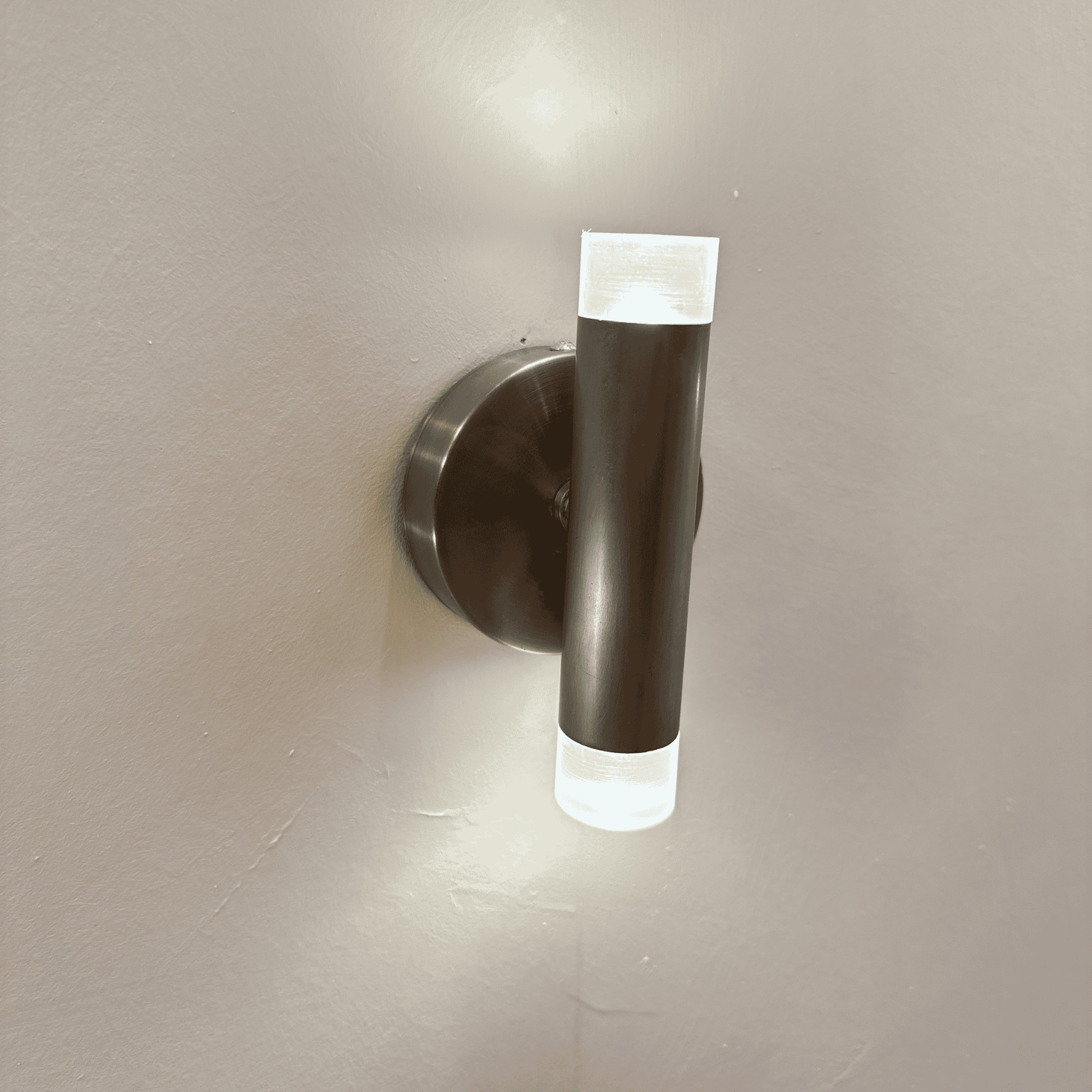 Vertical brushed metal LED wall sconce with frosted acrylic ends for soft, modern interior lighting.