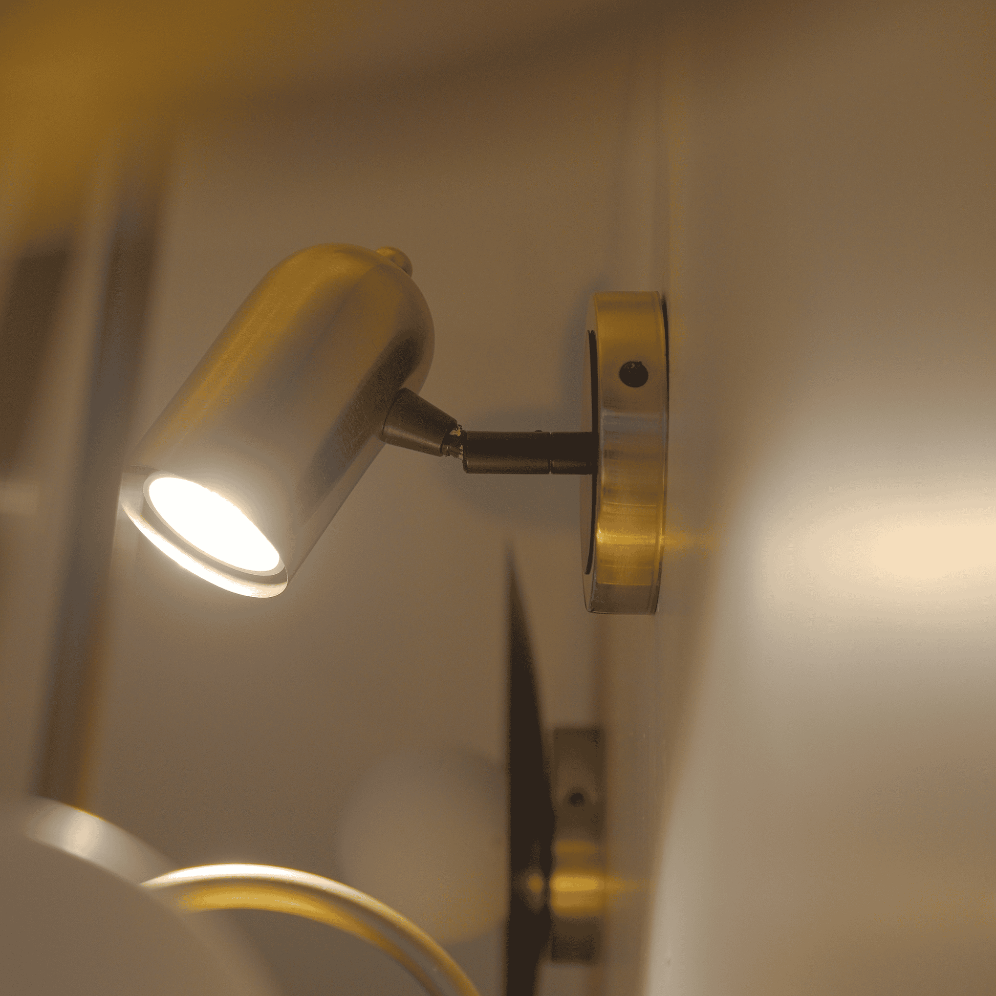 Slim brass wall sconce with articulating arm and cylindrical shade.