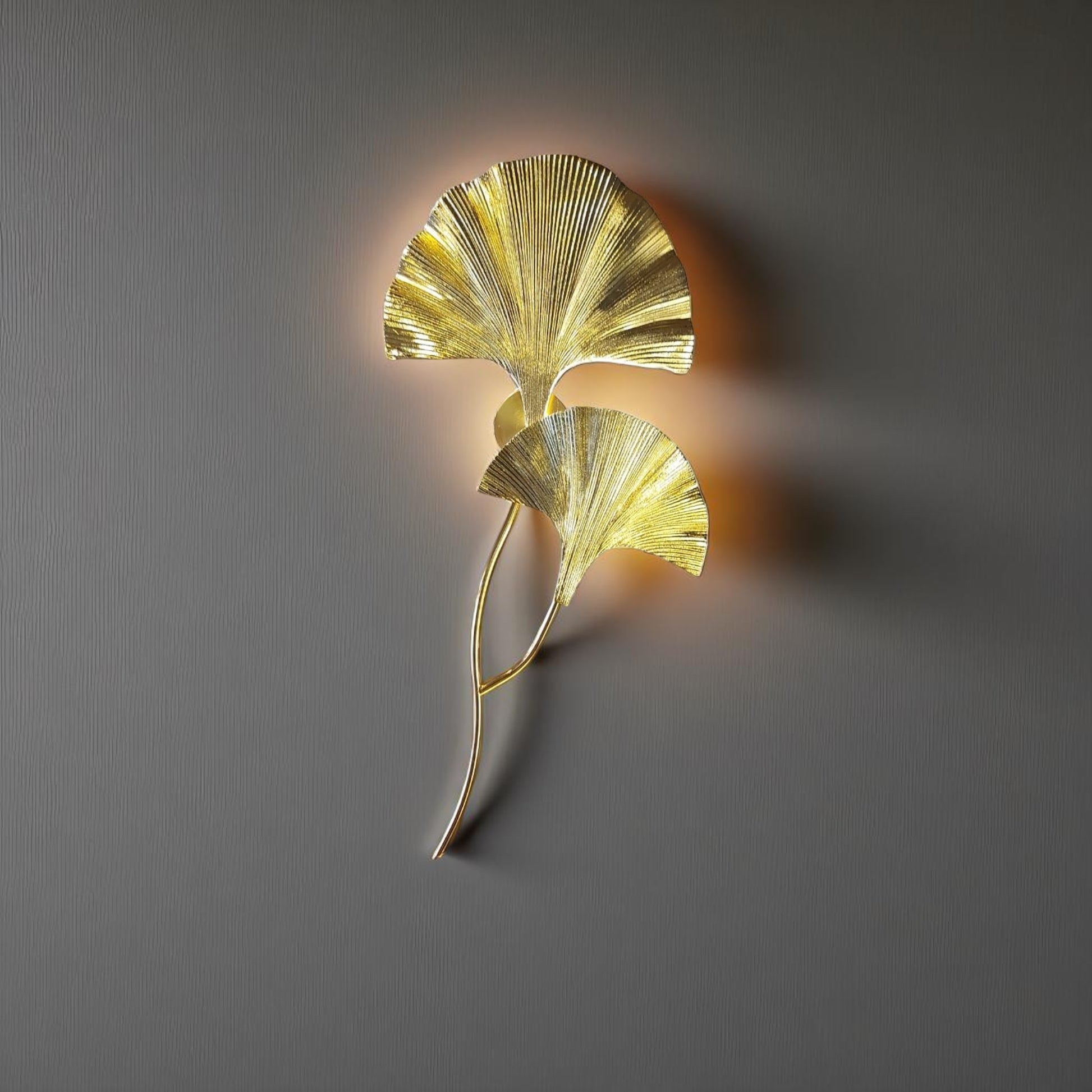 Tall sculptural wall sconce in a gold finish, mounted on a neutral interior wall