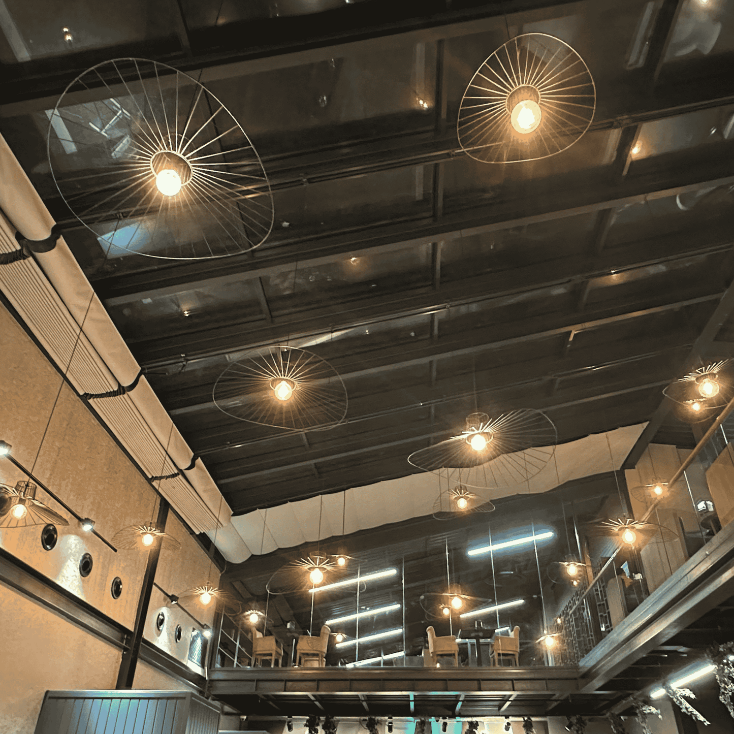 Cluster of straw hat pendant lights suspended from a vaulted ceiling in an industrial-style interior.