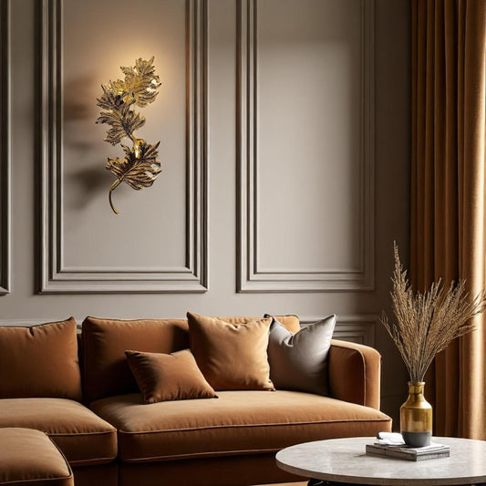 Sculptural gold brass Verona wall sconce mounted on a paneled taupe wall above a velvet sofa in a luxury living room
