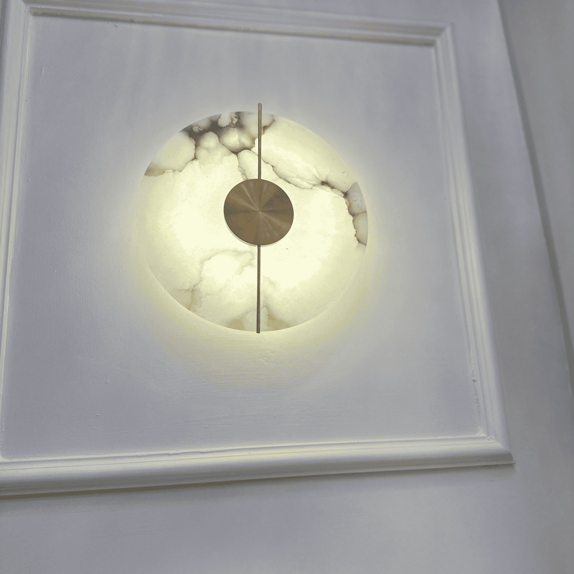 Vertical view of a backlit marble sconce on a light-colored wall.