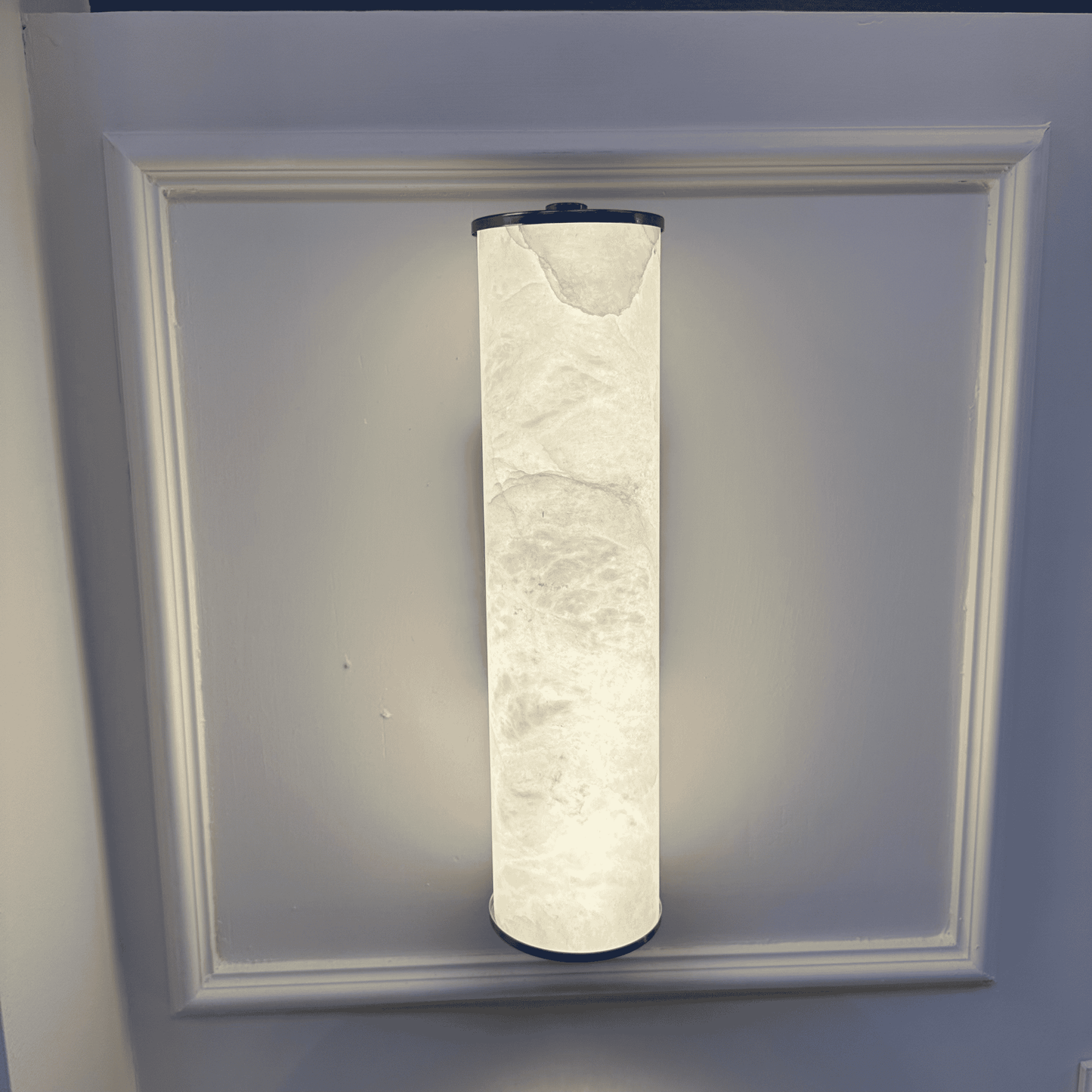 Vertical alabaster wall sconce emitting soft light with a clean and refined design.