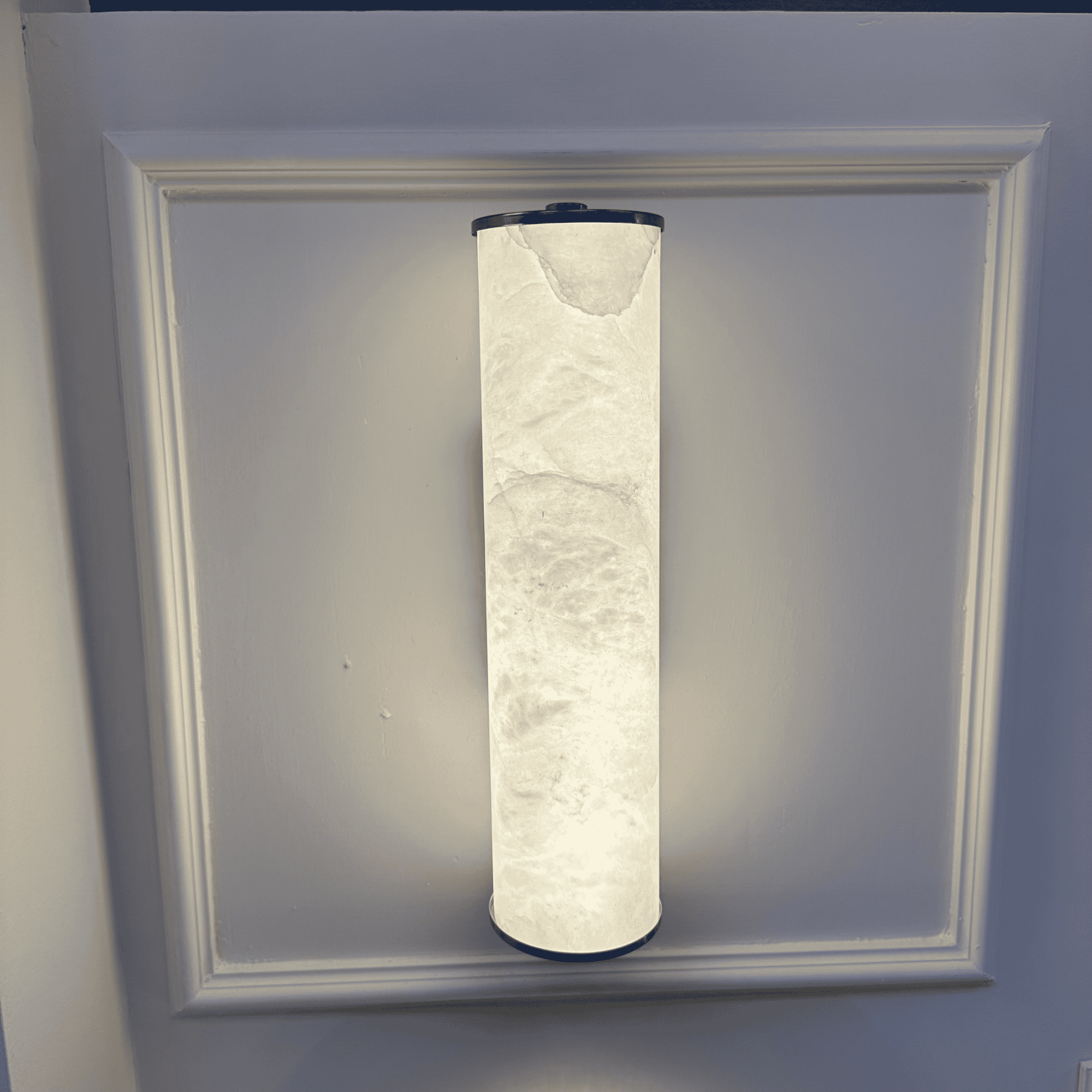 Vertical alabaster wall sconce emitting soft light with a clean and refined design.