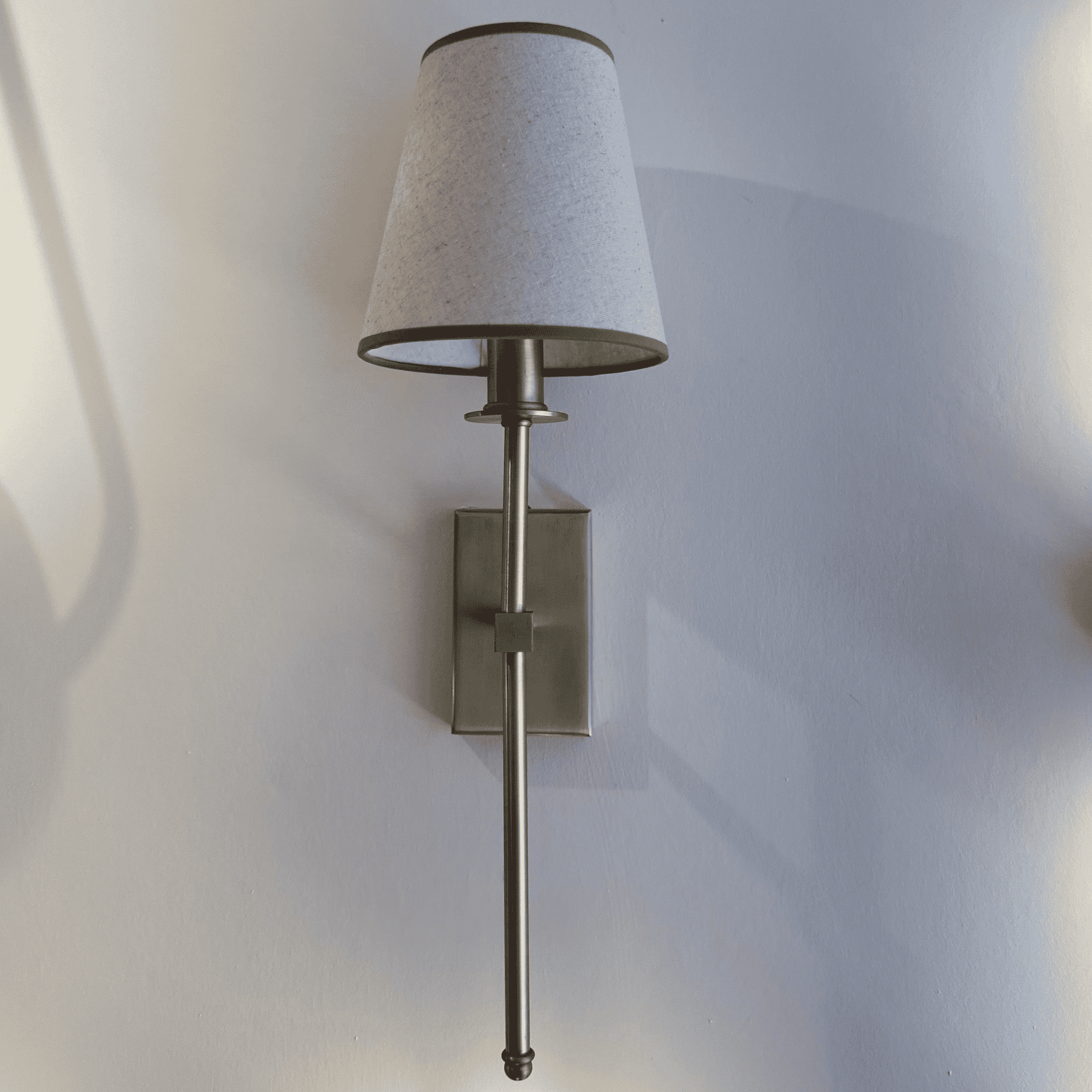 Wall-mounted lamp with a textured shade on a light gray wall