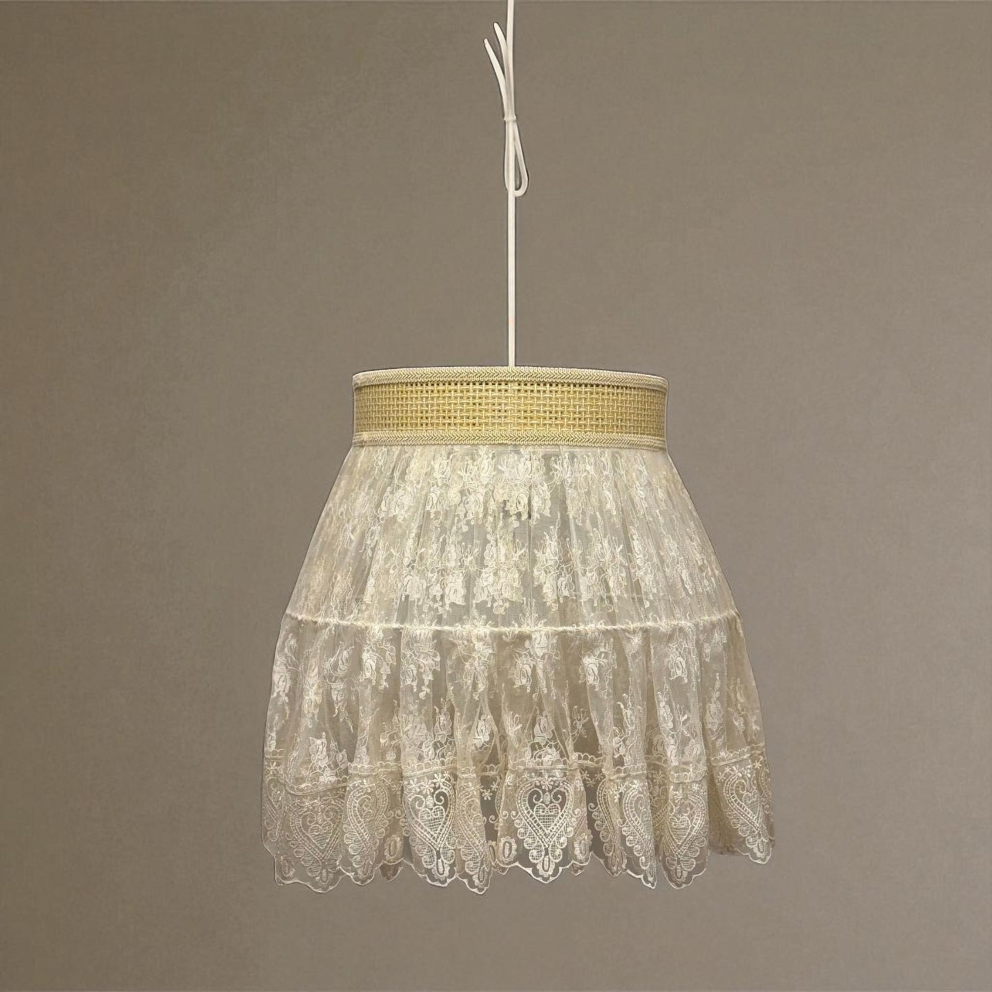 Vintage lace pendant light glowing softly in a formal room with traditional mirror and floral arrangement.