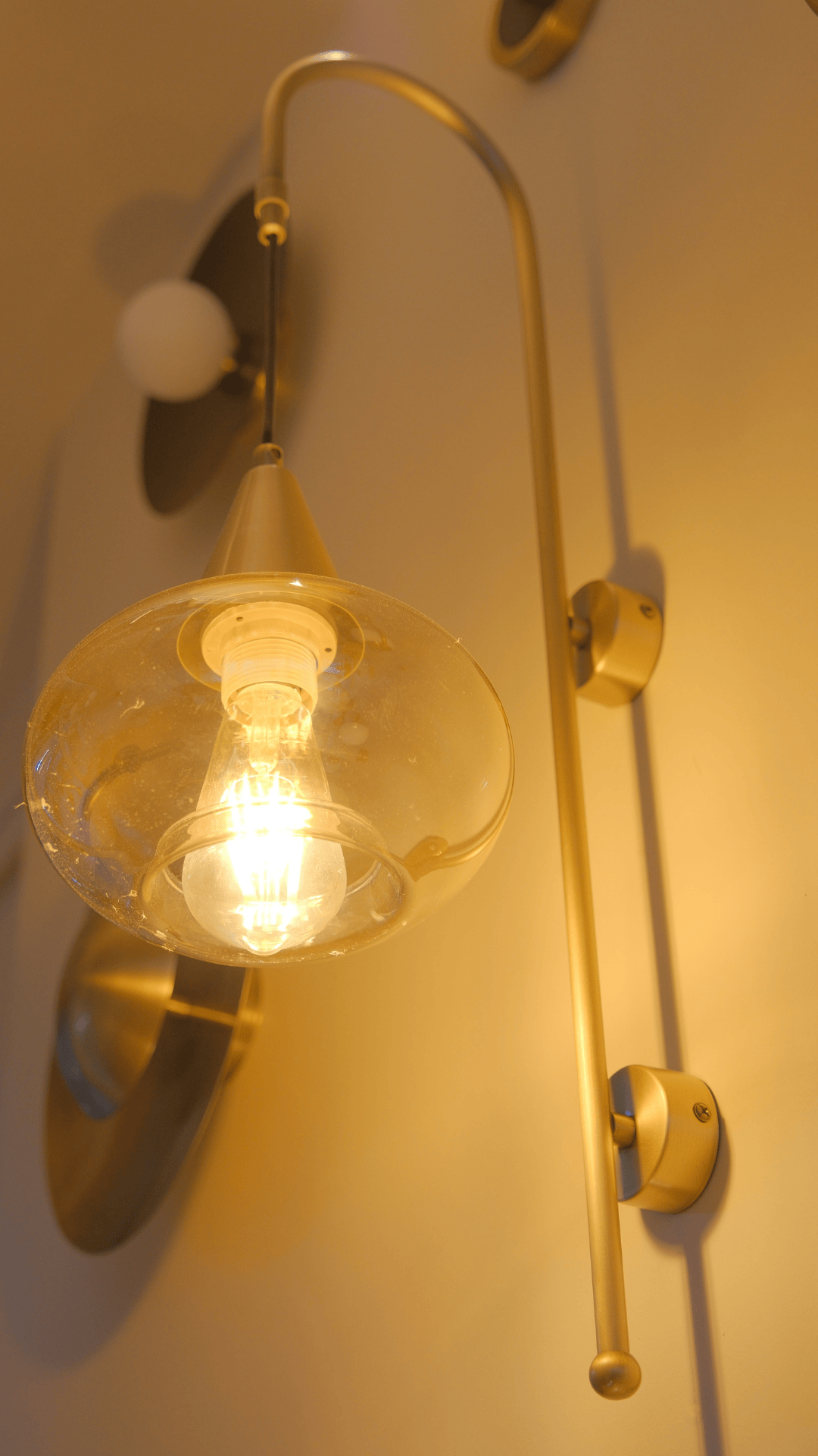 Vintage-style wall light with brass mount and clear round glass shade.