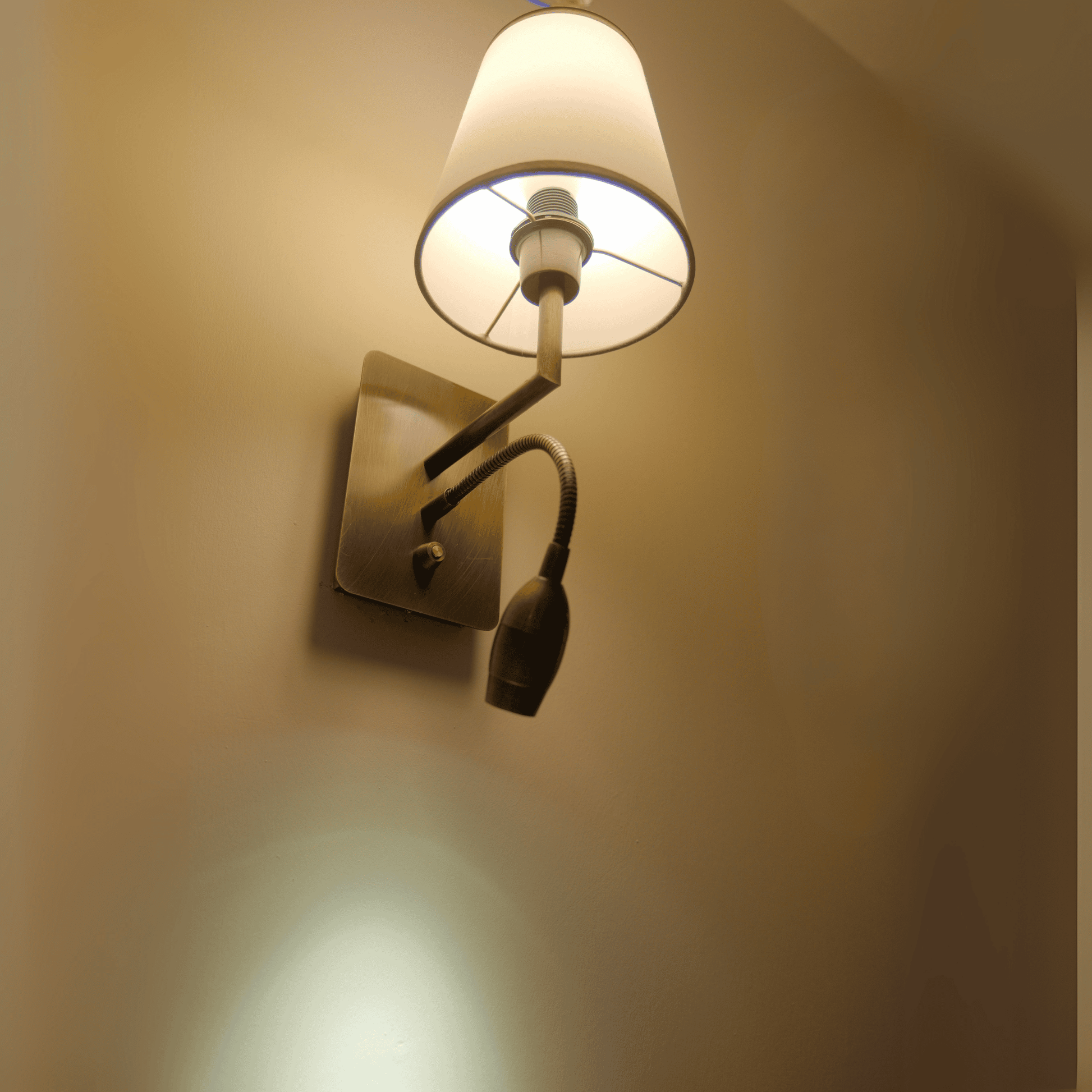 Wall sconce with white fabric shade and downward LED gooseneck spotlight.