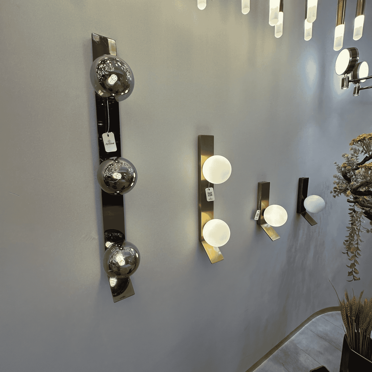 Display wall with multiple modern sconces in brass and black finishes featuring frosted and smoked glass globes.