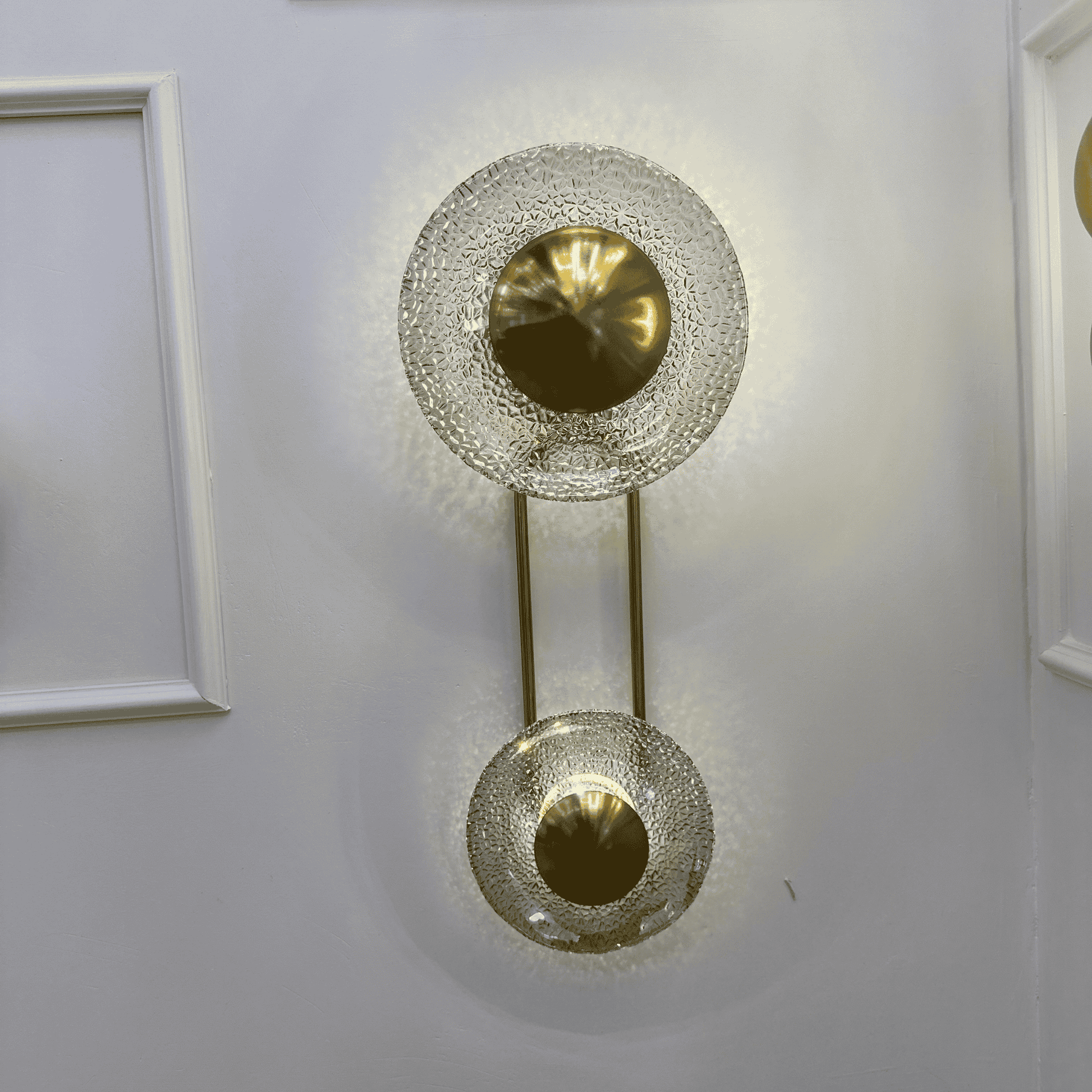 Brass-finish living room wall sconce with textured glass discs, vertical design.