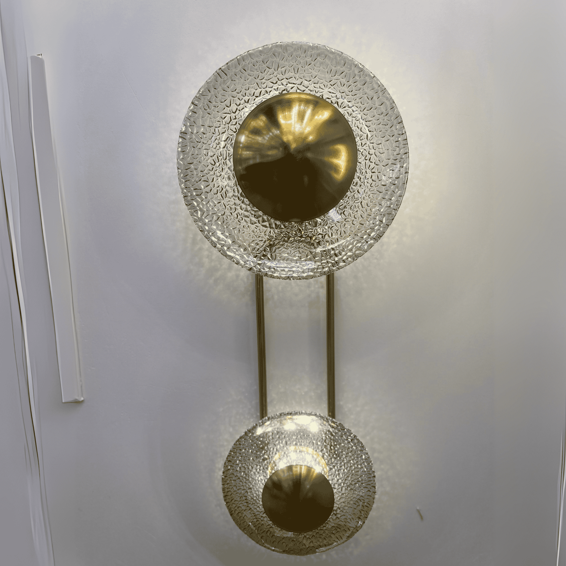 Front view of two-glass-disc brass wall sconce producing halo effect.
