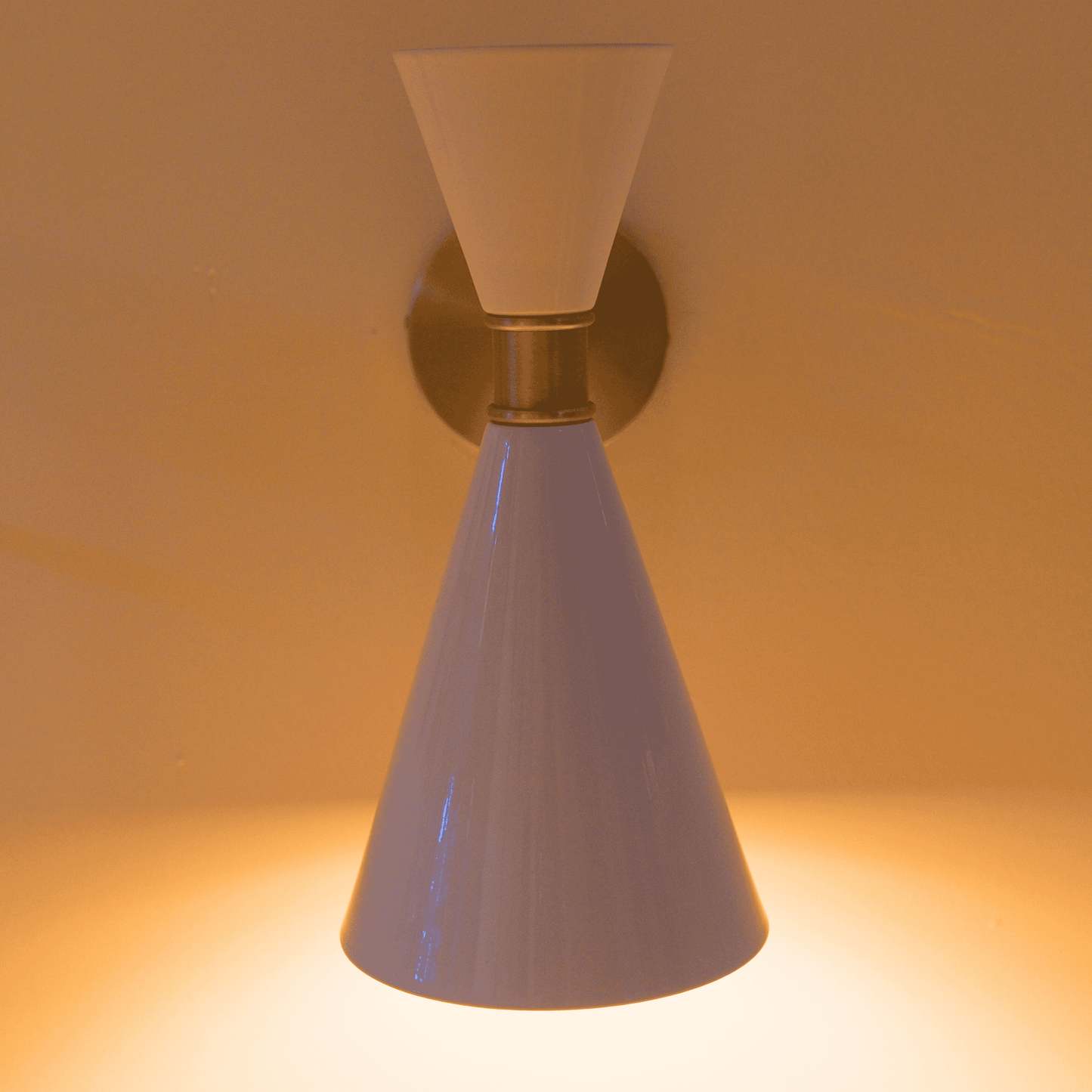 White dual-cone wall sconce in metal with modern design casting soft light upward and downward.