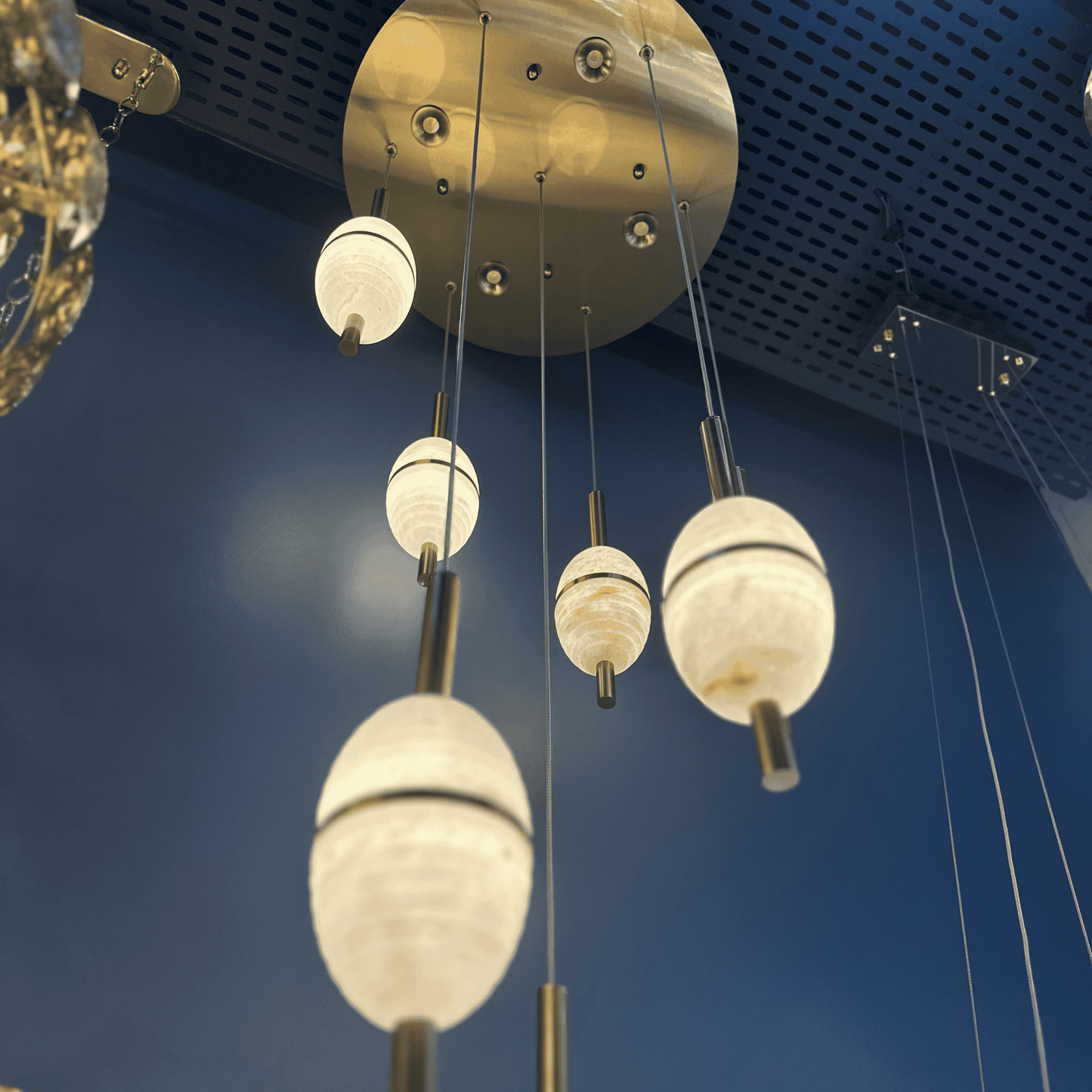 Cluster of alabaster pendant lights with cylindrical brass mounts hanging from a round ceiling plate.