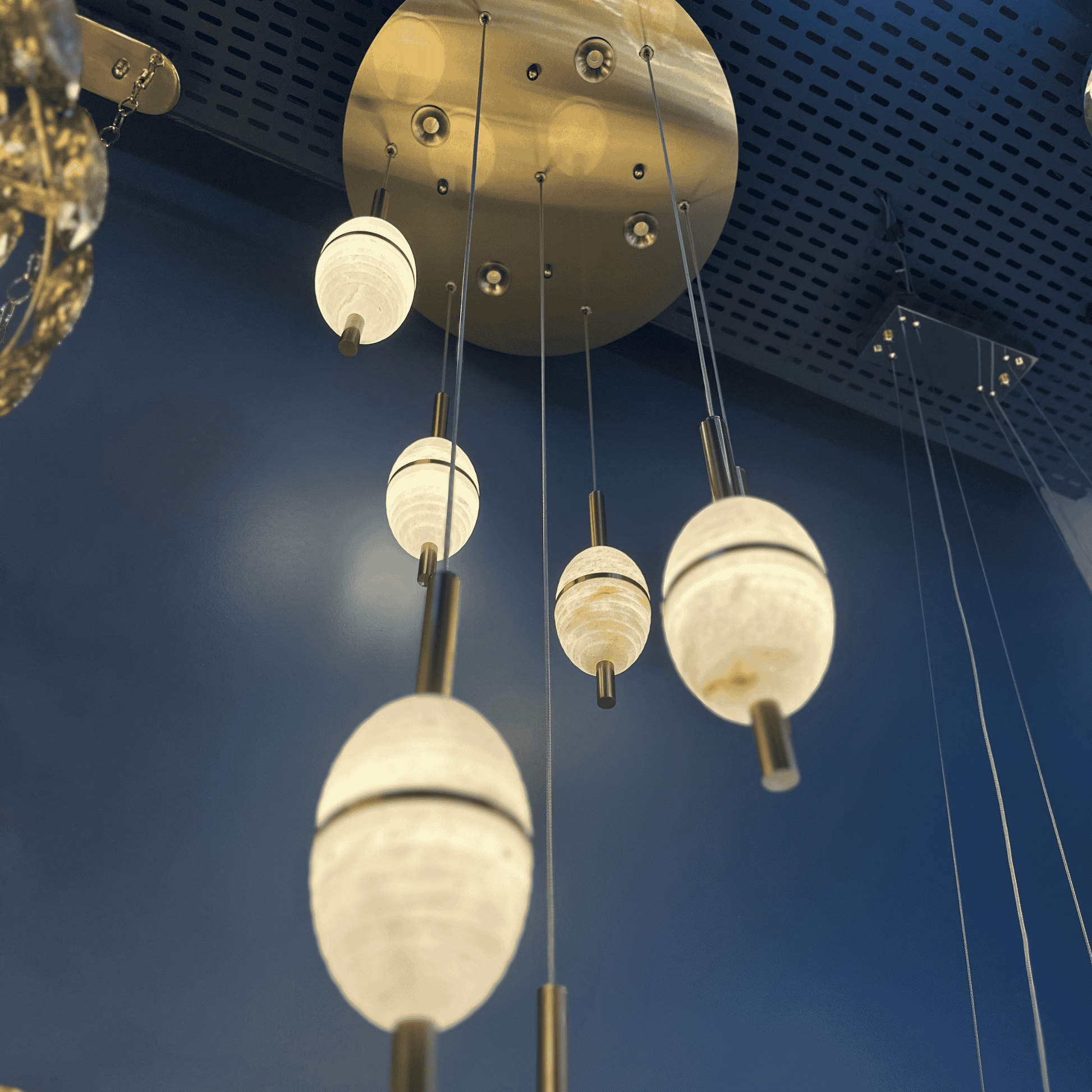 Cluster of alabaster pendant lights with cylindrical brass mounts hanging from a round ceiling plate.