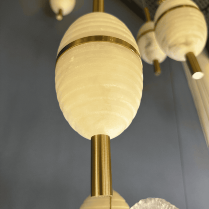 Close-up view of alabaster pendant light with ribbed texture and brass detailing against a soft blue background.