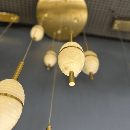 Alabaster pendant lights viewed from below, showing modern brass mount and linear suspension.