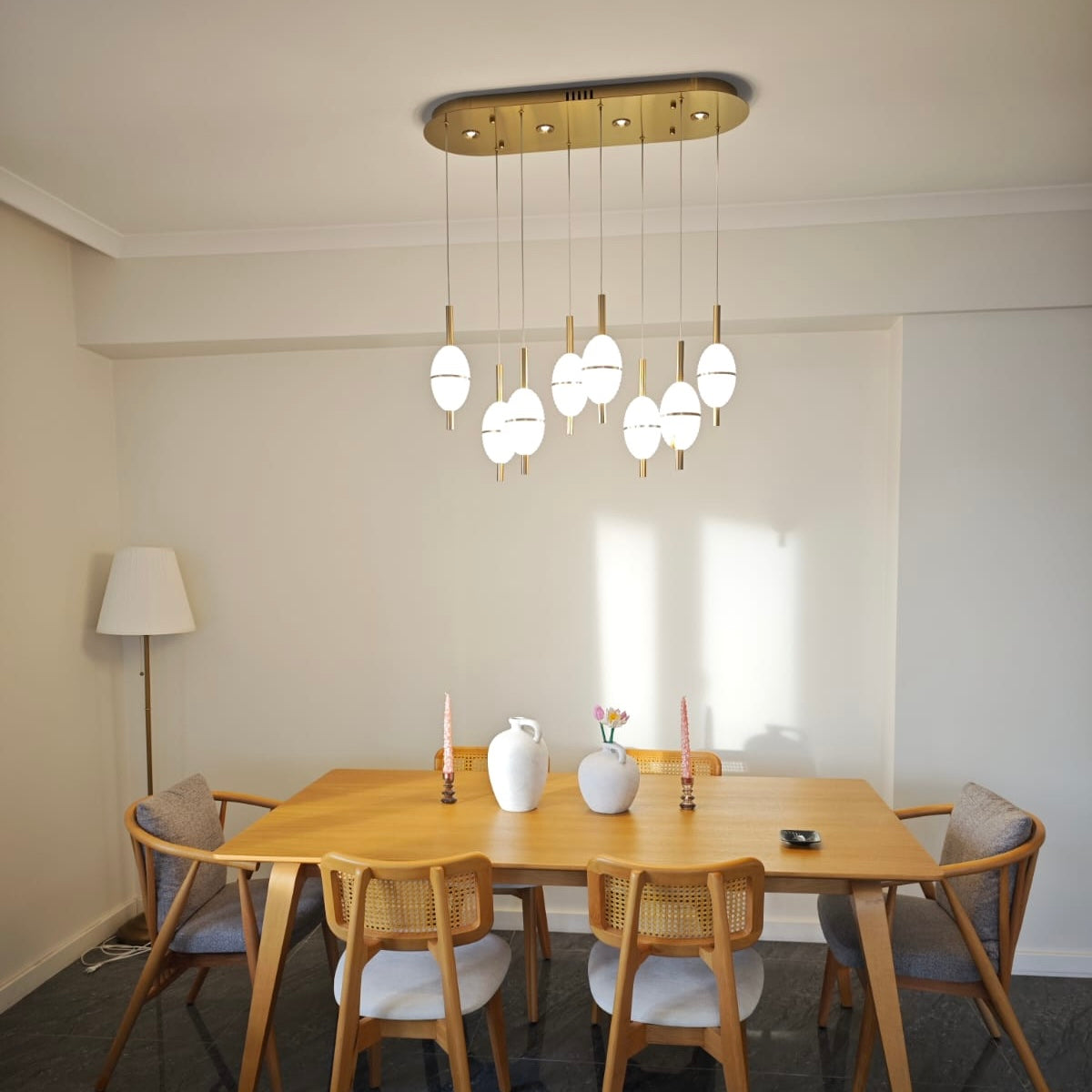 Close-up of alabaster pendant light over a wooden dining table with soft neutral interior tones and contemporary seating.