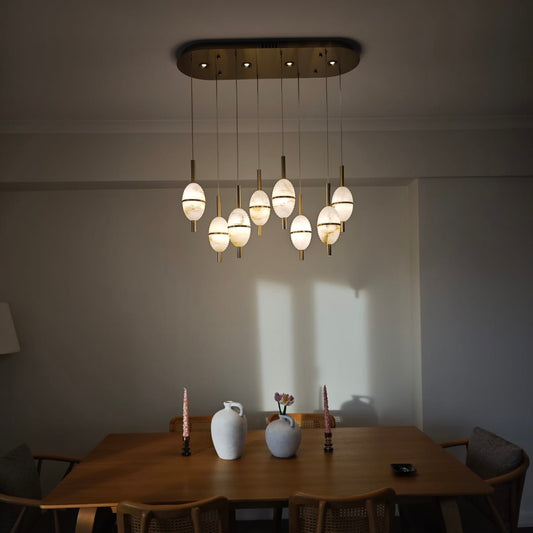 Evening lighting ambiance created by alabaster pendant lights suspended above a warm-toned dining area.