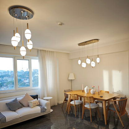 Alabaster pendant lights elegantly illuminate a modern open-plan living and dining space with natural daylight and neutral interiors.