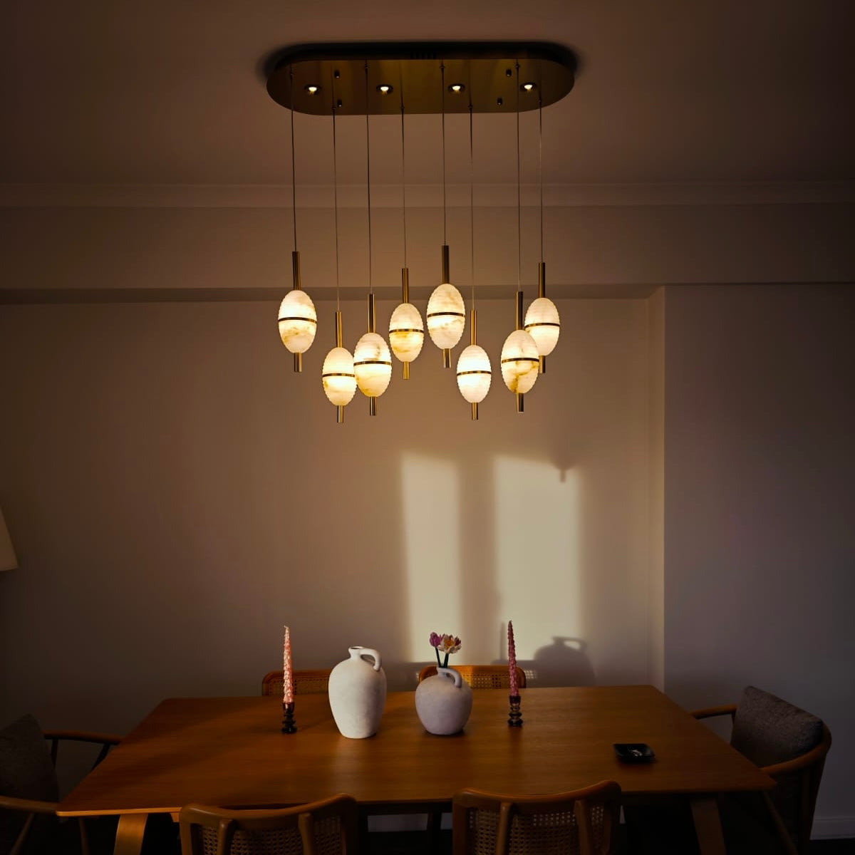 Soft golden lighting from alabaster pendants highlights a warm, modern dining room arrangement.