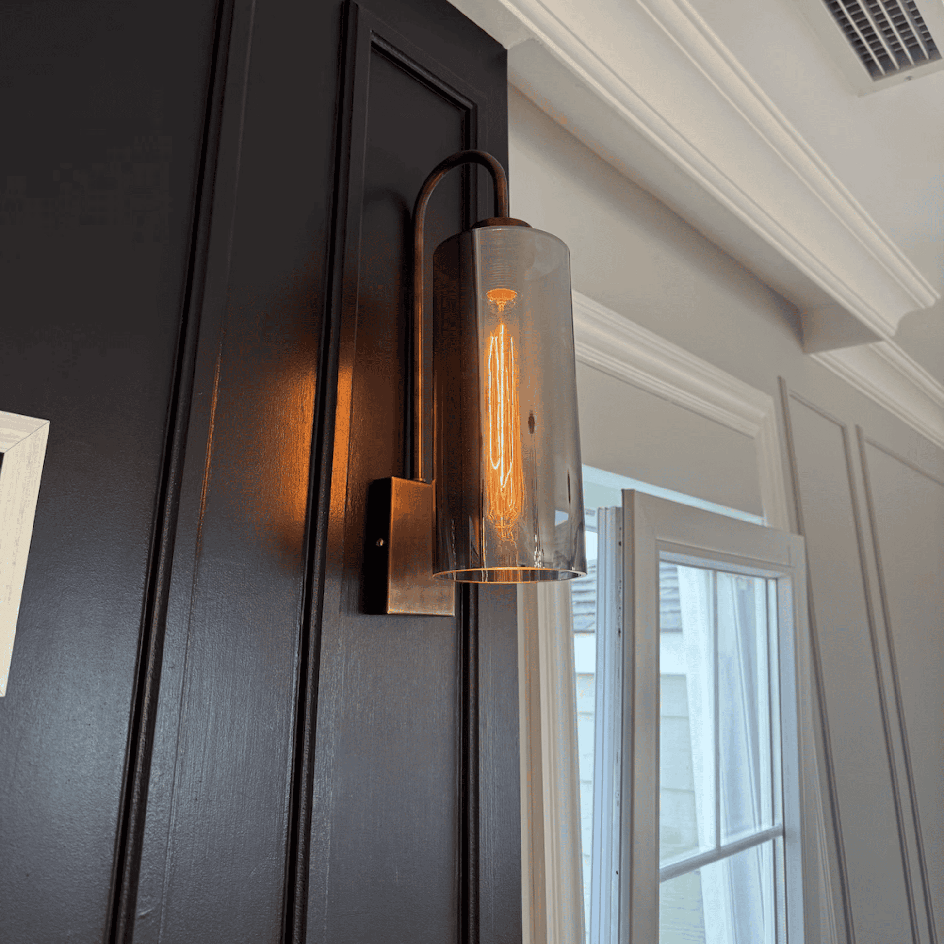 Angled view of blown glass wall sconce with antique hardware and warm glow.
