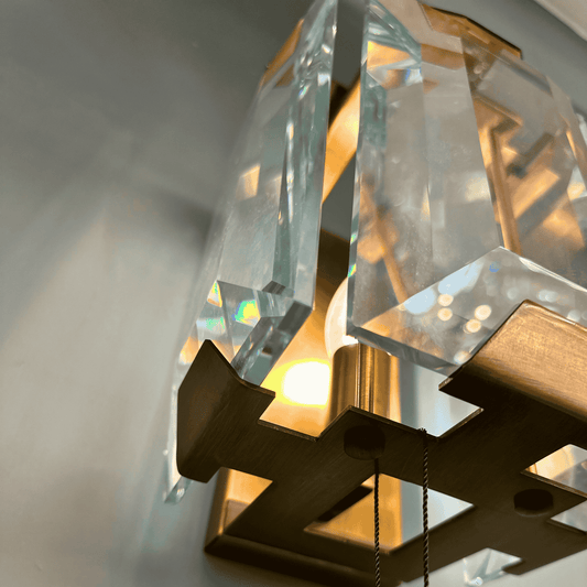 Elegant wall-mounted sconce featuring faceted crystal glass and gold frame