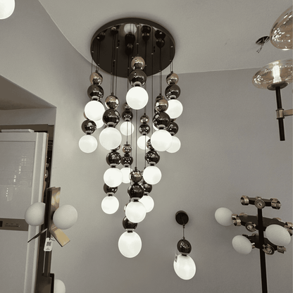 A tiered pendant lighting fixture with black and white glass globes, designed for modern interior applications.