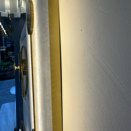 Side view of alabaster wall light fixture with brass frame and subtle glow.