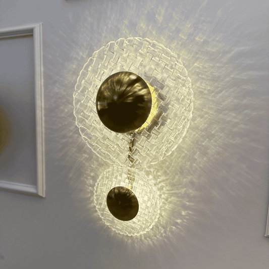 Brass wall sconce with two clear glass diffusers casting soft ambient lighting in the entryway.