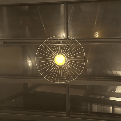 Straw hat pendant light glowing centrally against dark glass panels in an industrial interior.