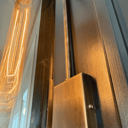 Close-up of blown glass wall sconce showing antique hardware and glowing filament bulb.