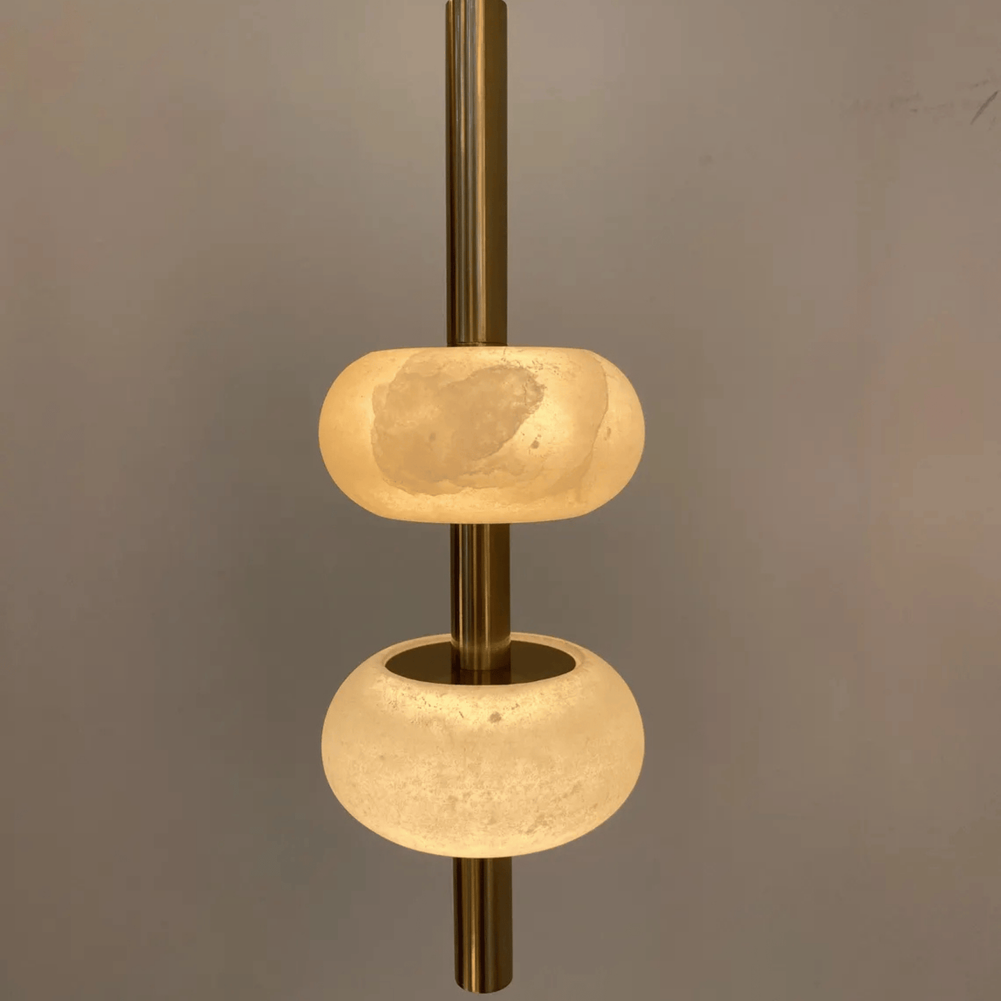 Detailed close-up of alabaster pendant light with translucent stone and brass rod.