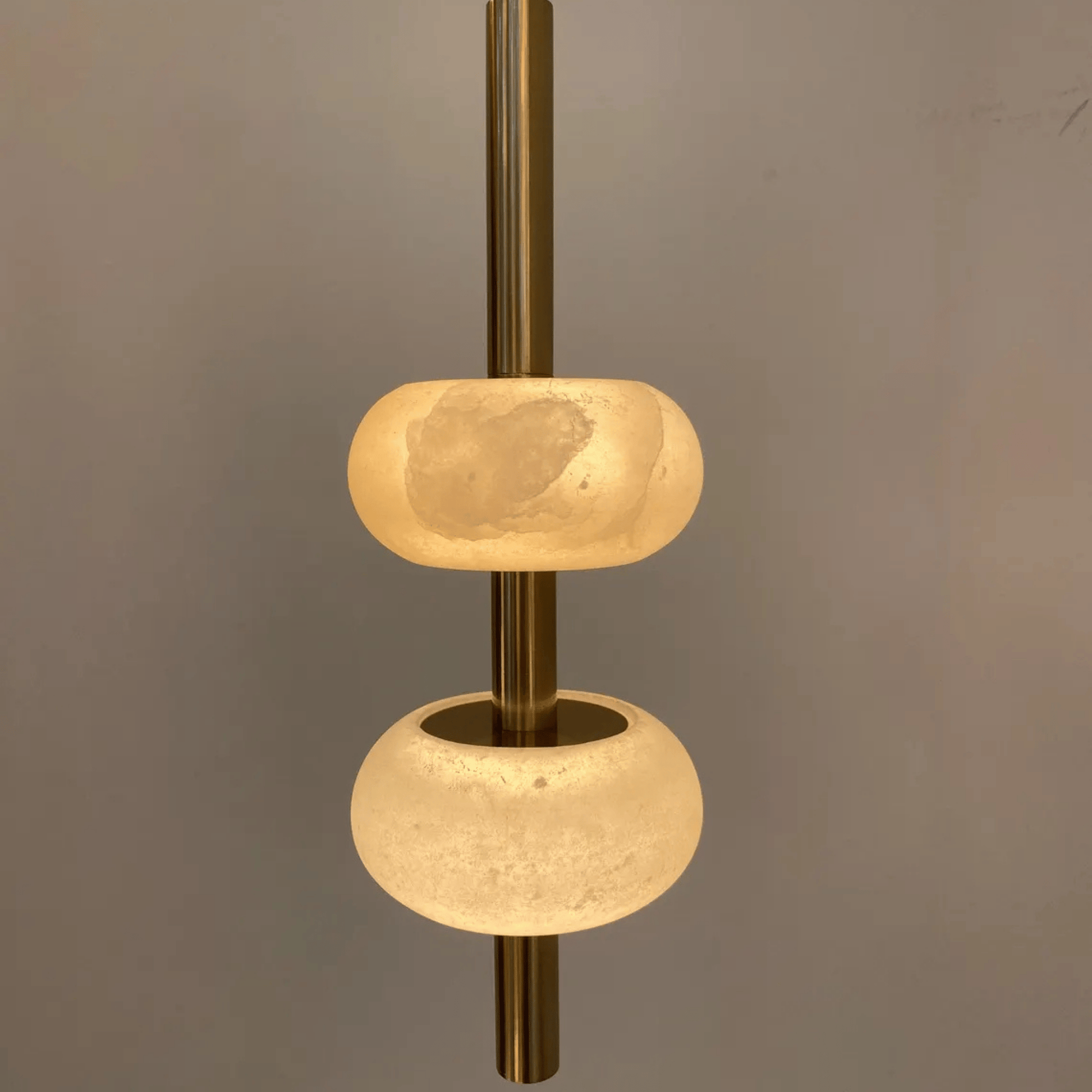 Detailed close-up of alabaster pendant light with translucent stone and brass rod.