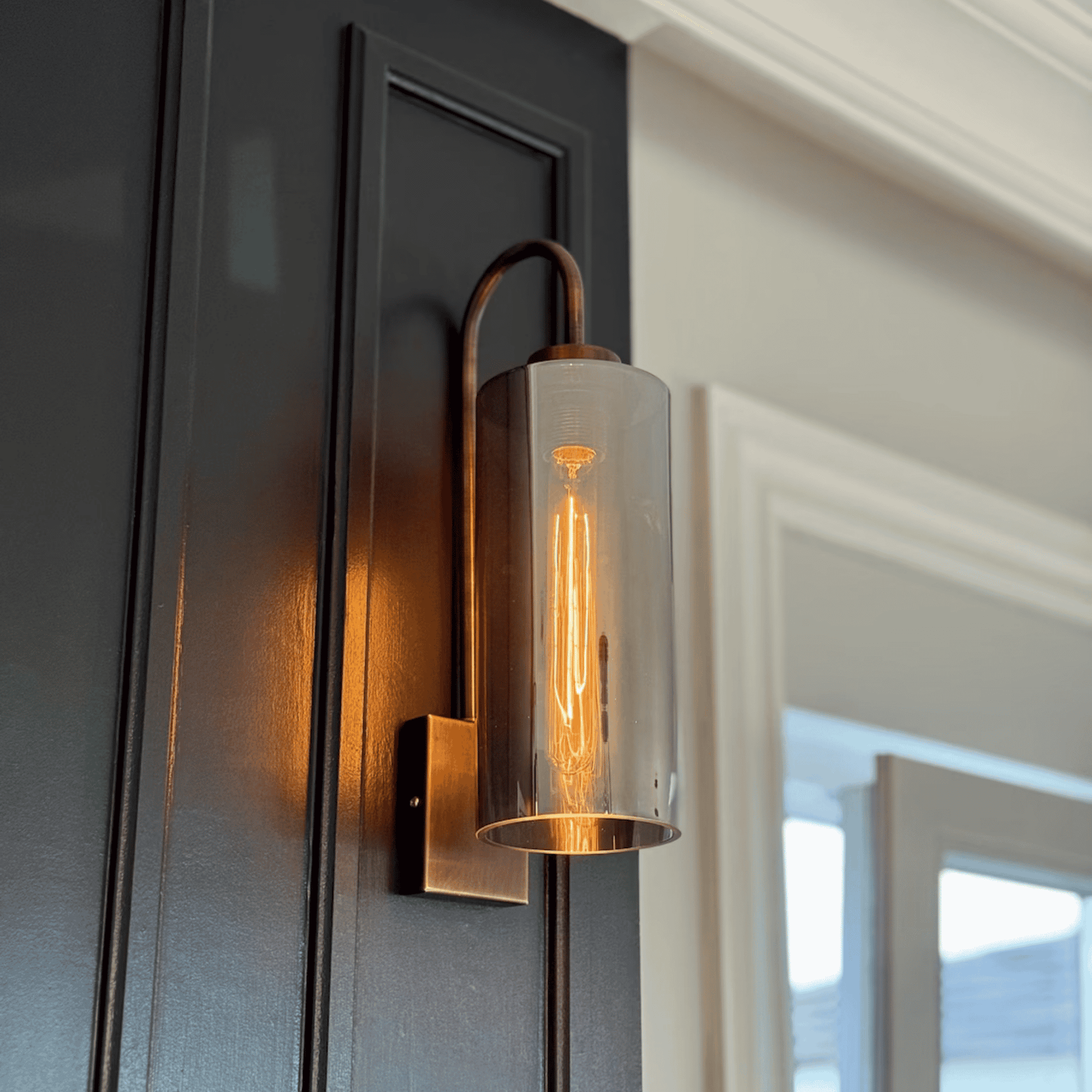 Contemporary blown glass wall sconce with clear glass shade and antique hardware