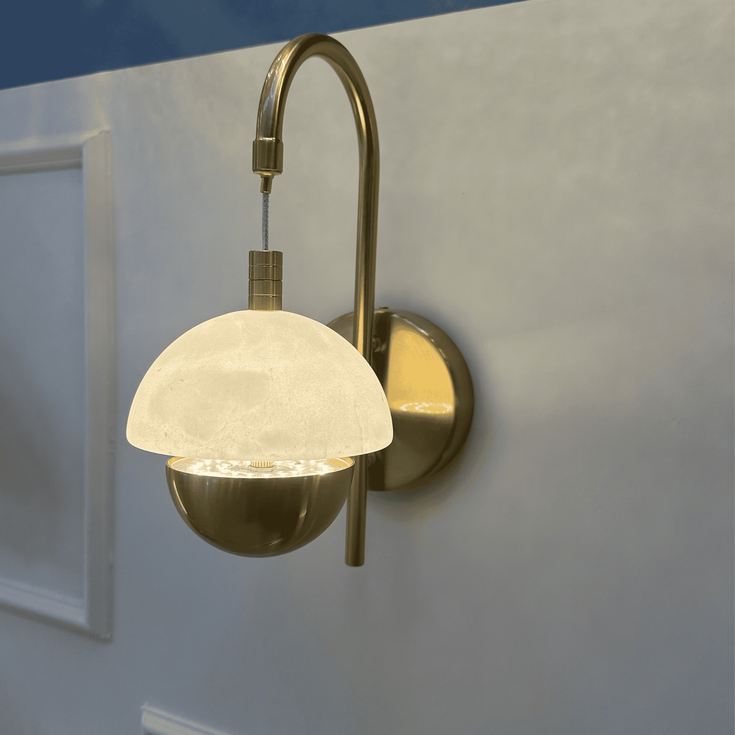 Brass arched marble sconce with a contemporary design mounted on a neutral wall.