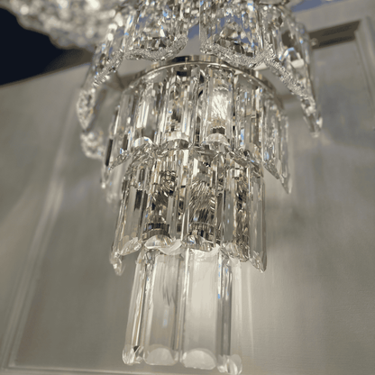 Detailed close-up of a tiered crystal wall sconce light with reflective clear glass prisms.